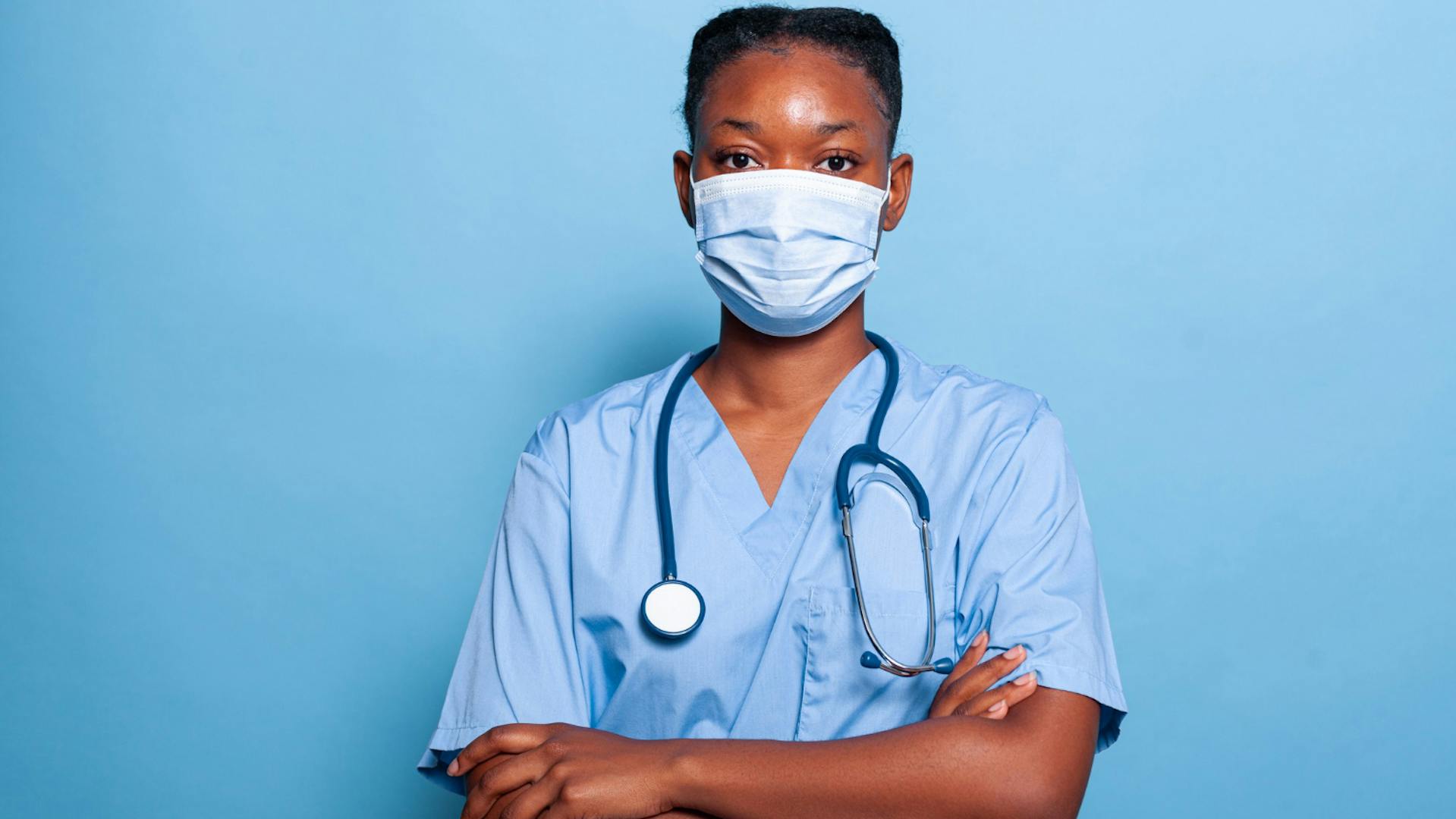médica com roupa cirúrgica azul claro com parede também azul ao fundo