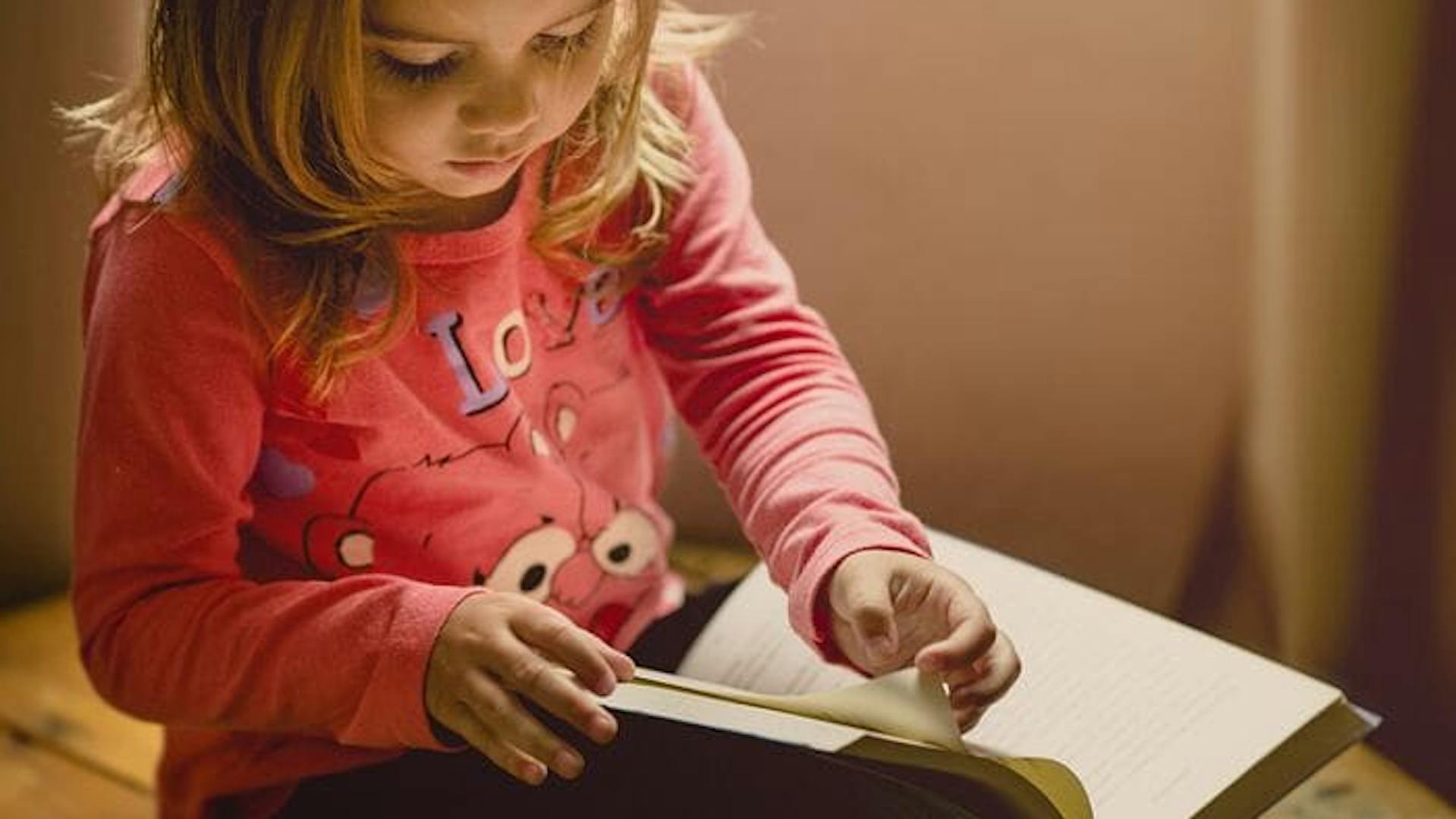Criança com um livro na mão lendo 