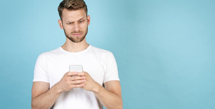 homem com duvida olhando para celular