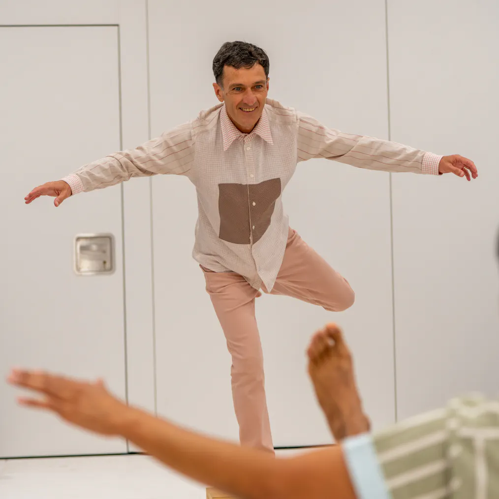 An artist balancing on a block with their hands up in the air