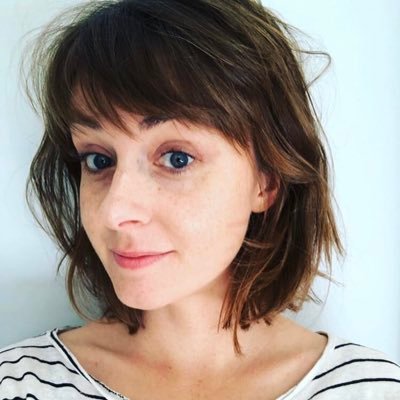 A women with short brown hair looking at the camera against a white background