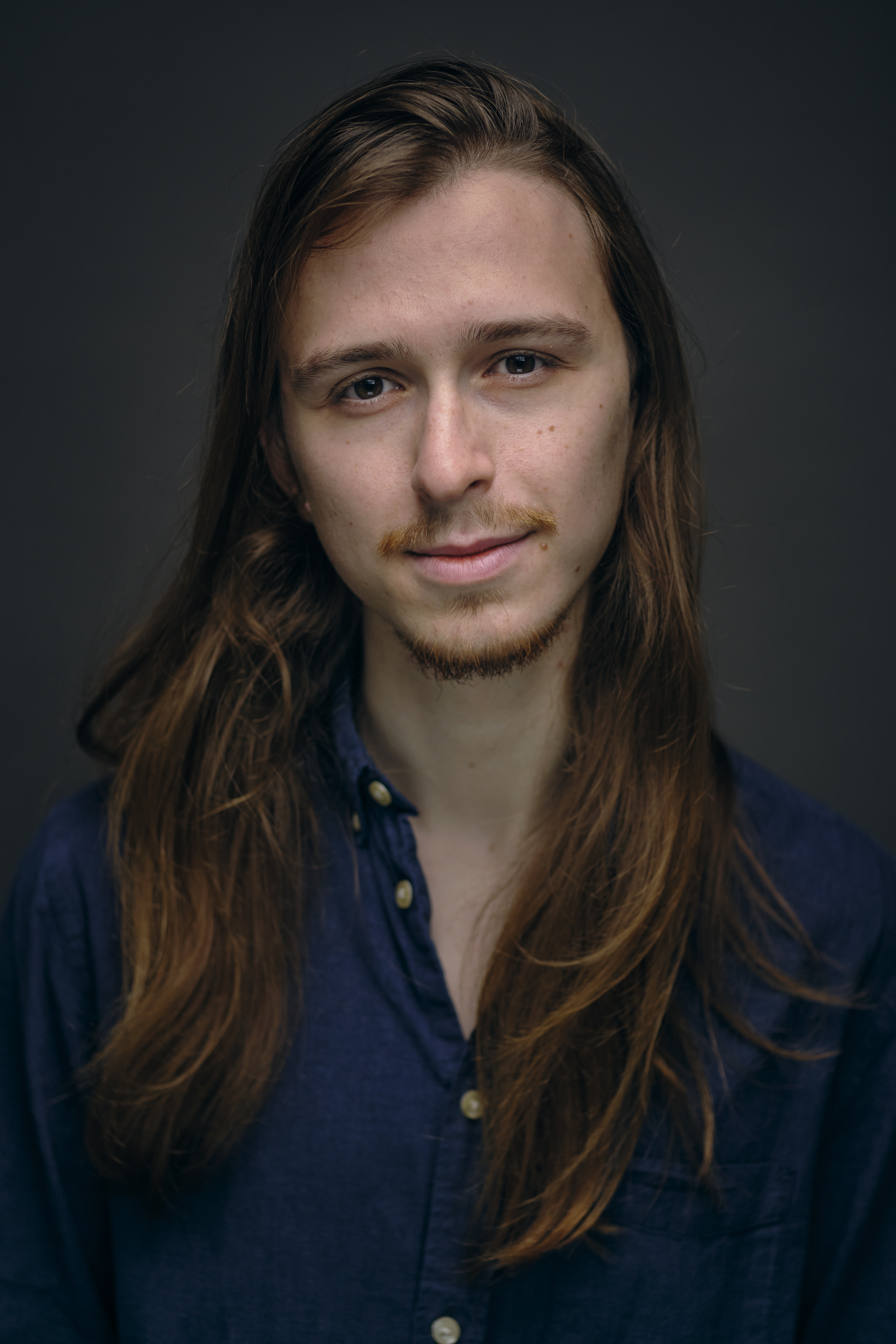 A person looking at the camera in fornt of a dark background