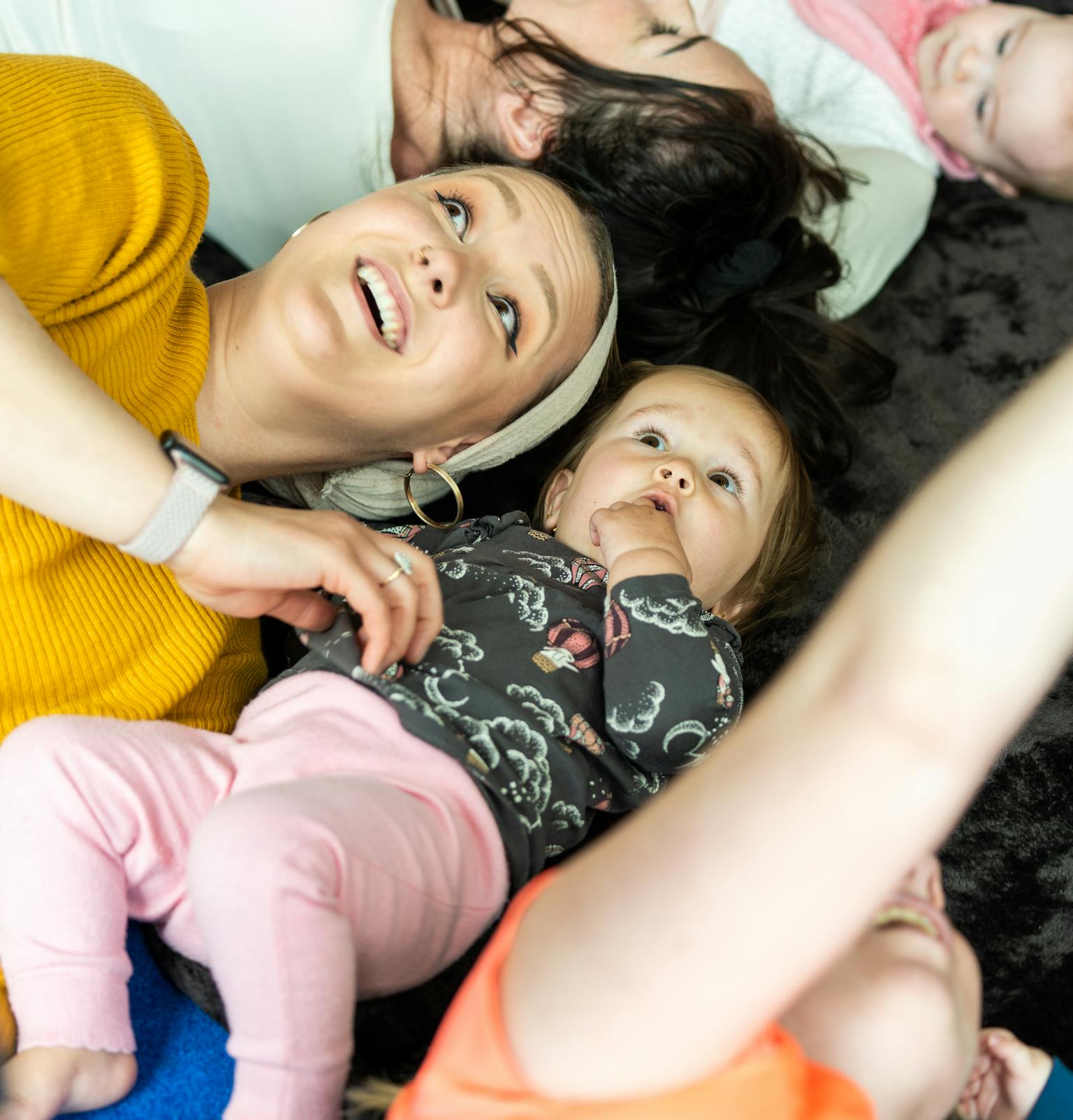 A young child and their parent/carer lying on a mat and looking up at the ceiling.