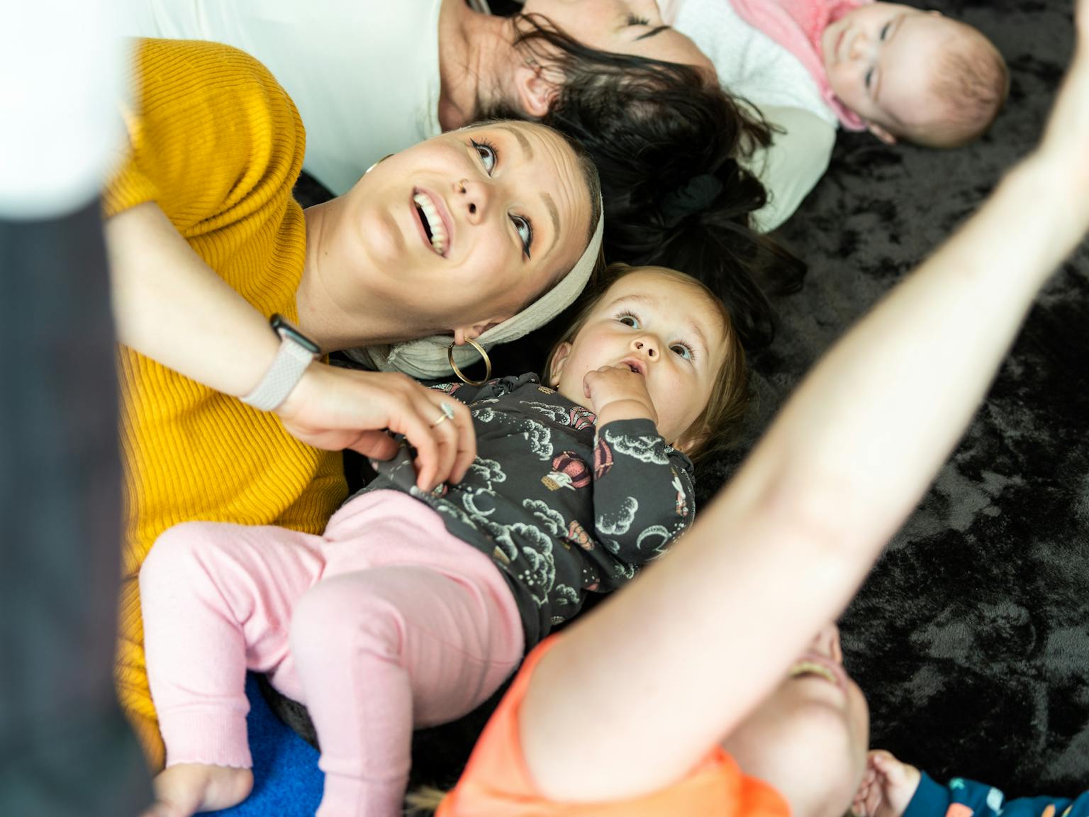A young child and their parent/carer lying on a mat and looking up at the ceiling.
