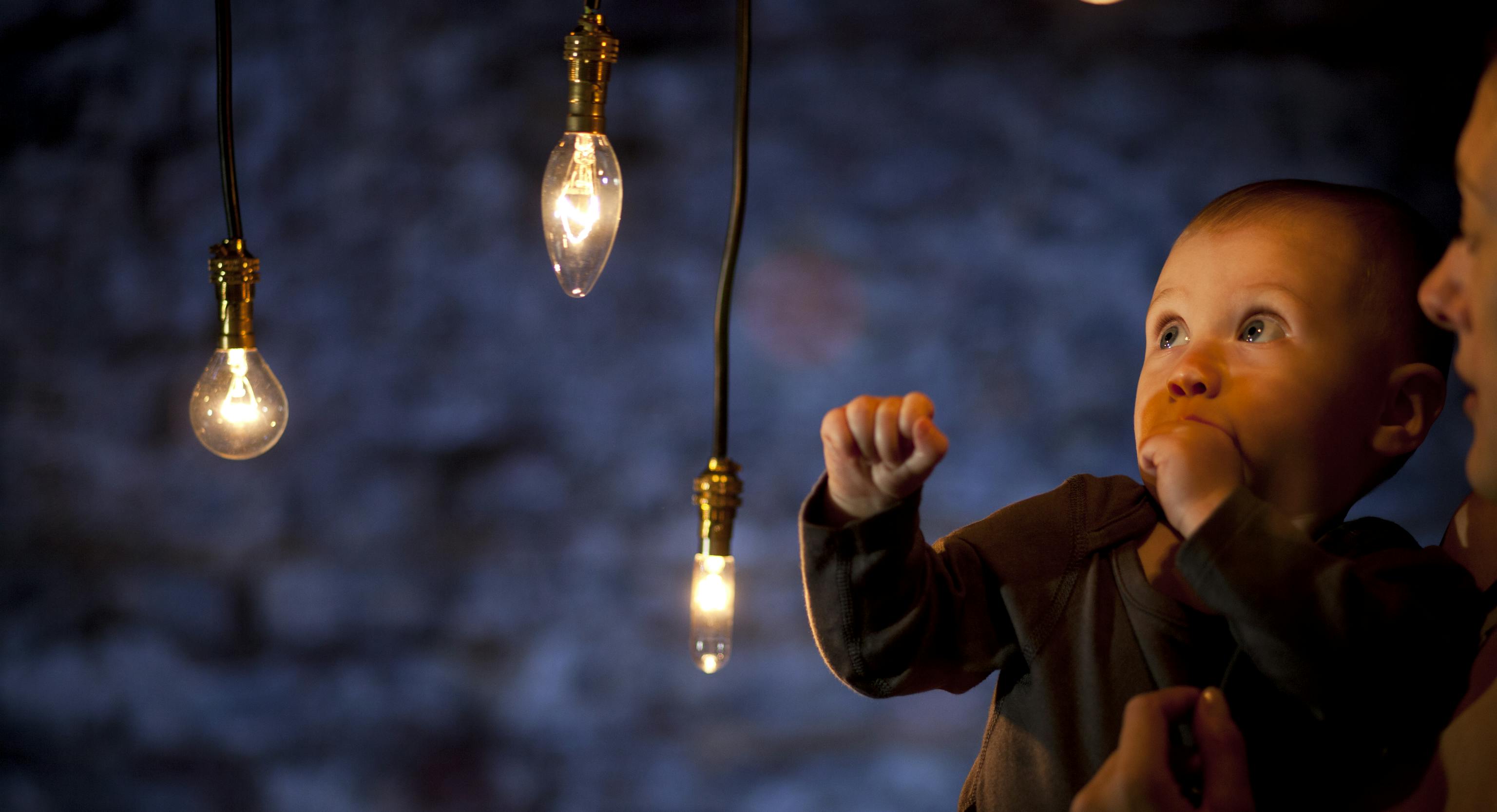 A baby and mother in a darkly lit room surrounded by lights