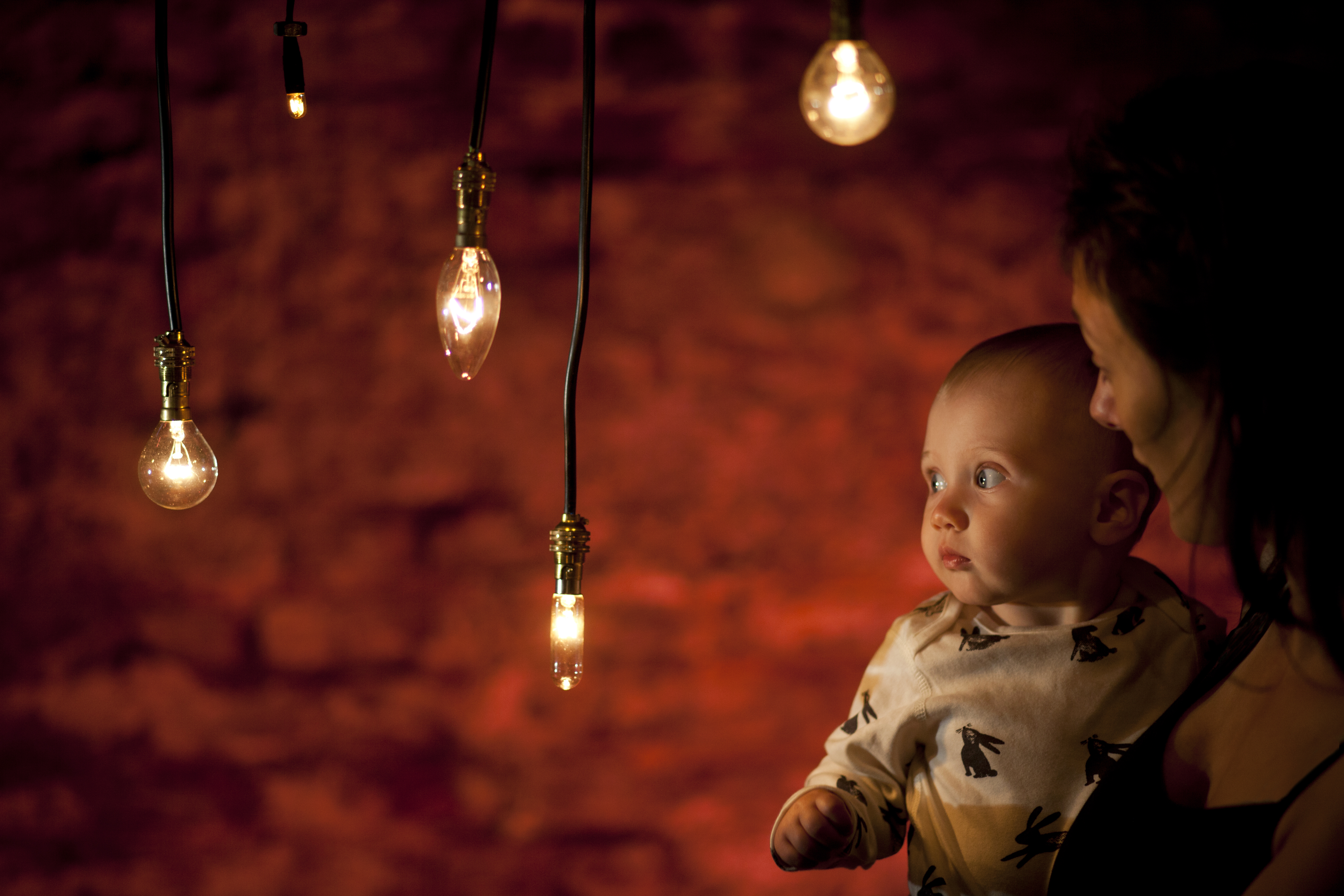 A baby and mother in a darkly lit room surrounded by light