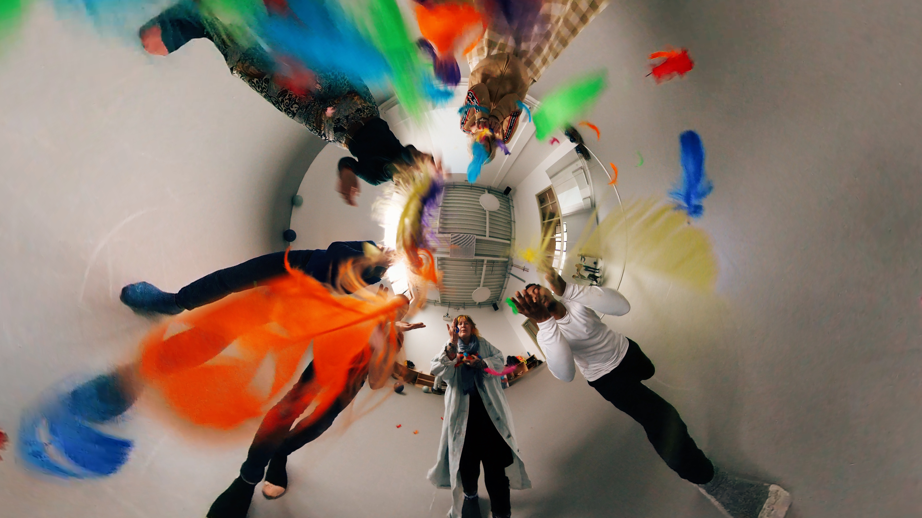 An image of artists throwing colourful feathers at the screen 
