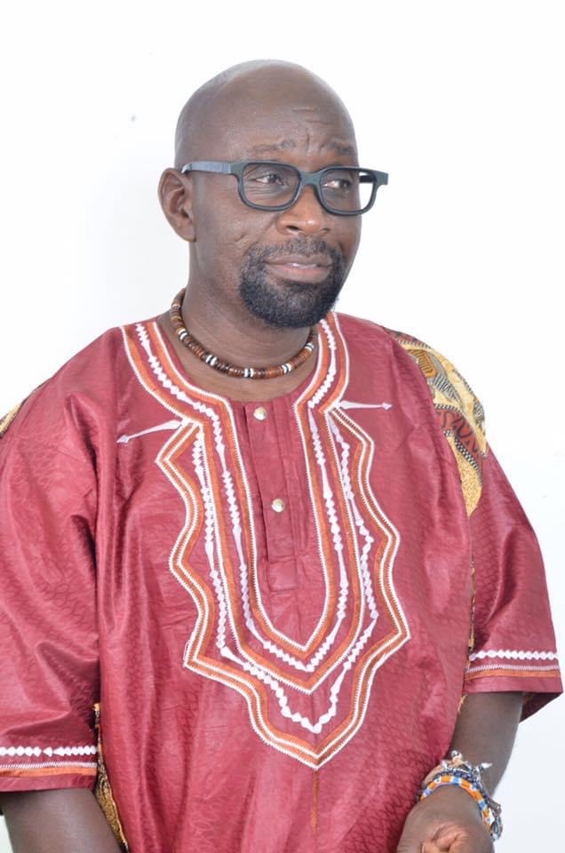 Lucky is stood in fornt of a white background and looking away from the camera. He is wearing a colourful print shirt.