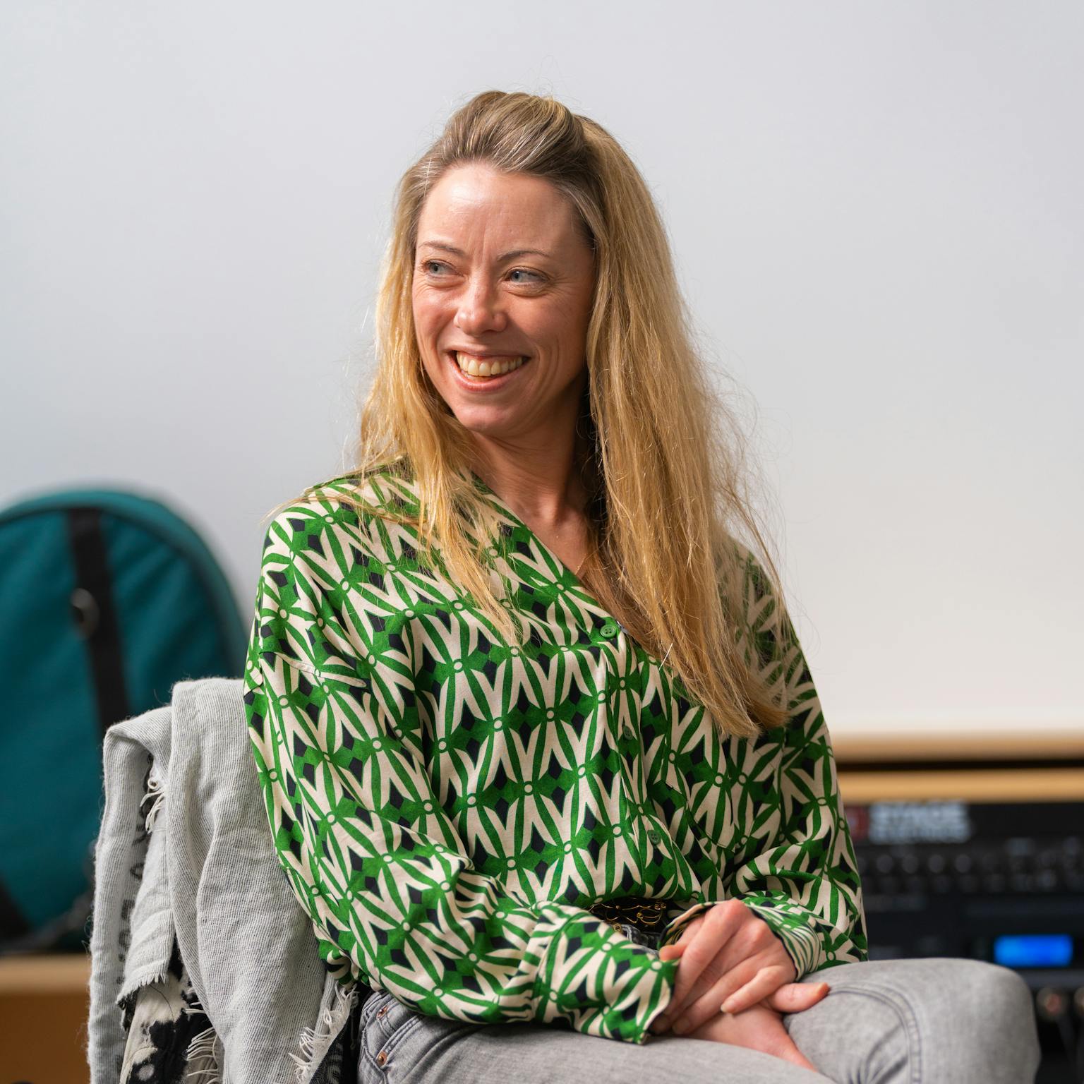 A person sat in a chair, looking to their side and smiling.