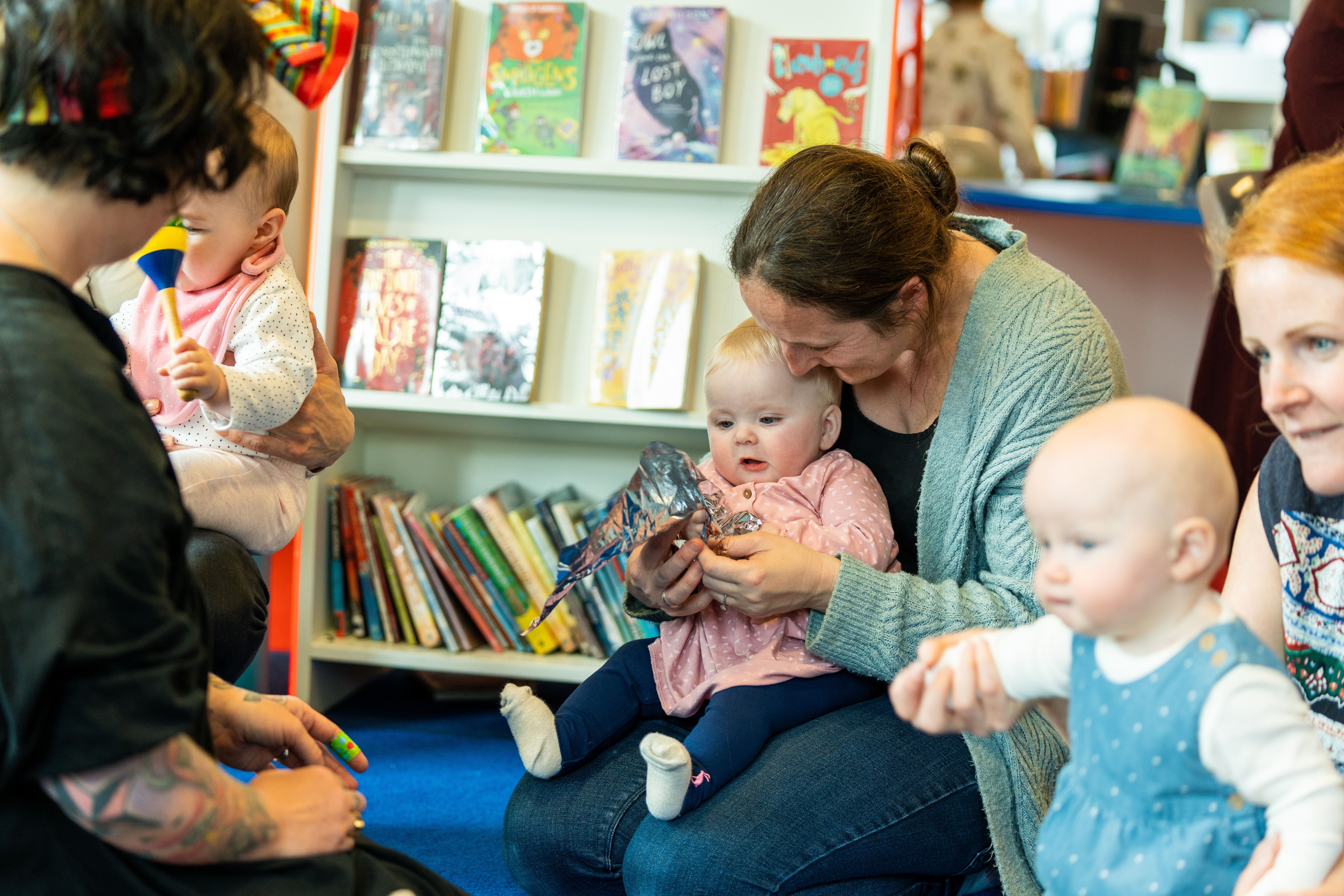 A group of parent/carers and baby in a library engaging with each other