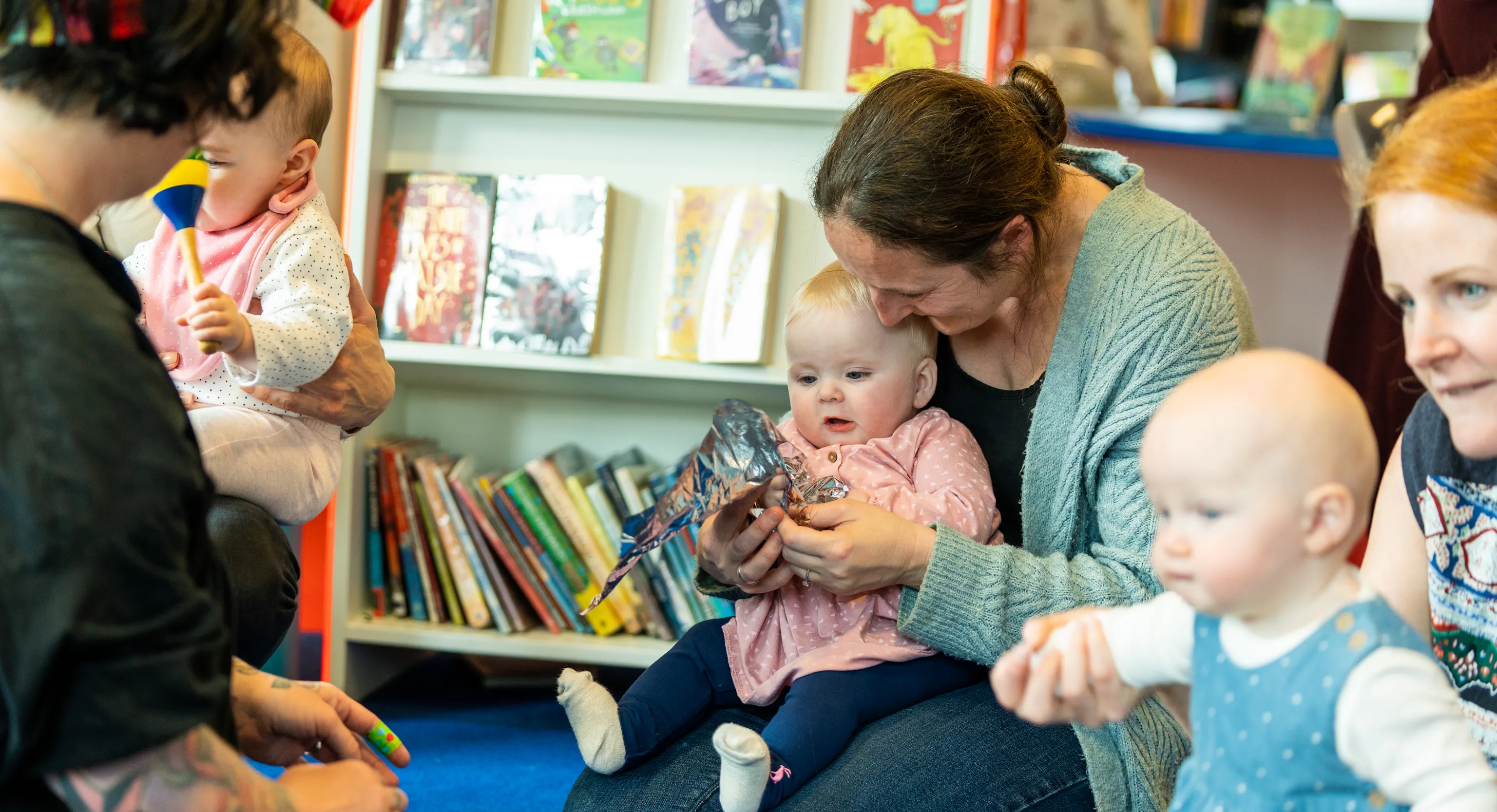 A group of parent/carers and baby in a library engaging with each other