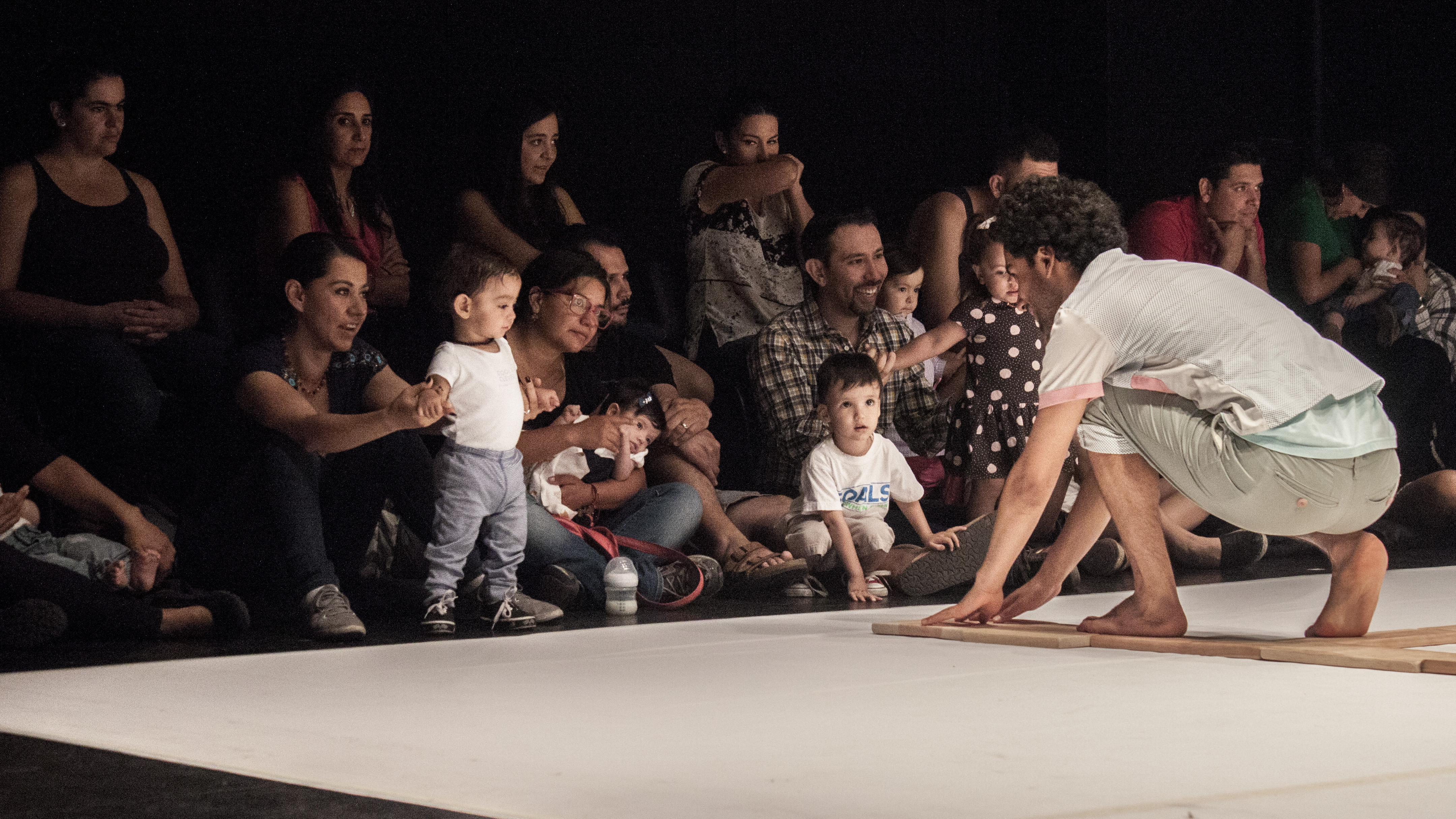 An artist on stage engaging with a group of children and their parents/carers