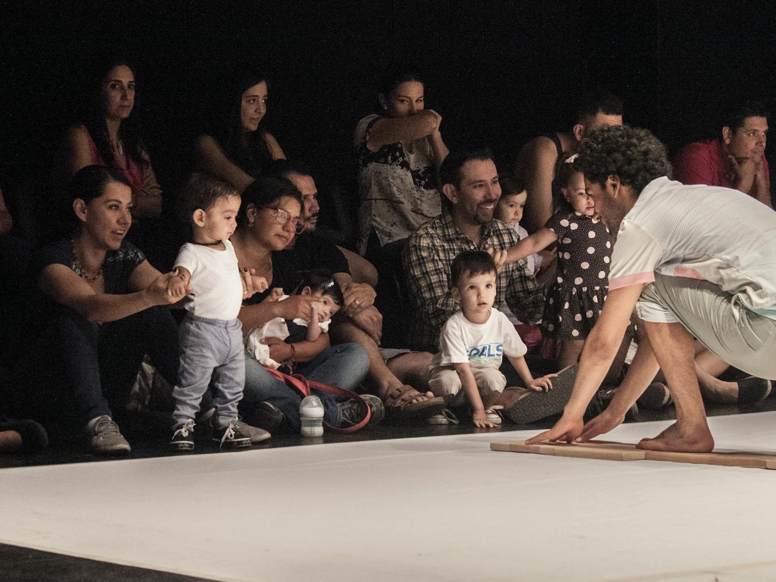 An artist on stage engaging with a group of children and their parents/carers