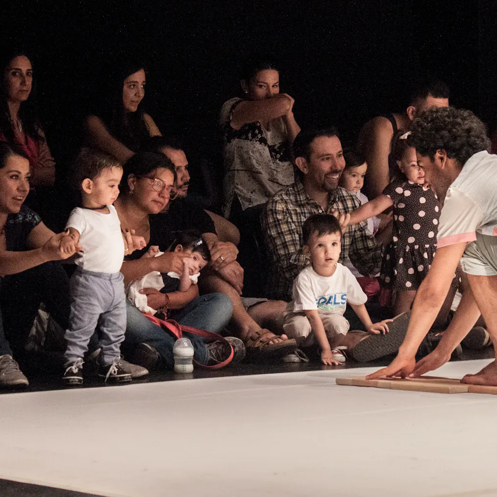 An artist on stage engaging with a group of children and their parents/carers