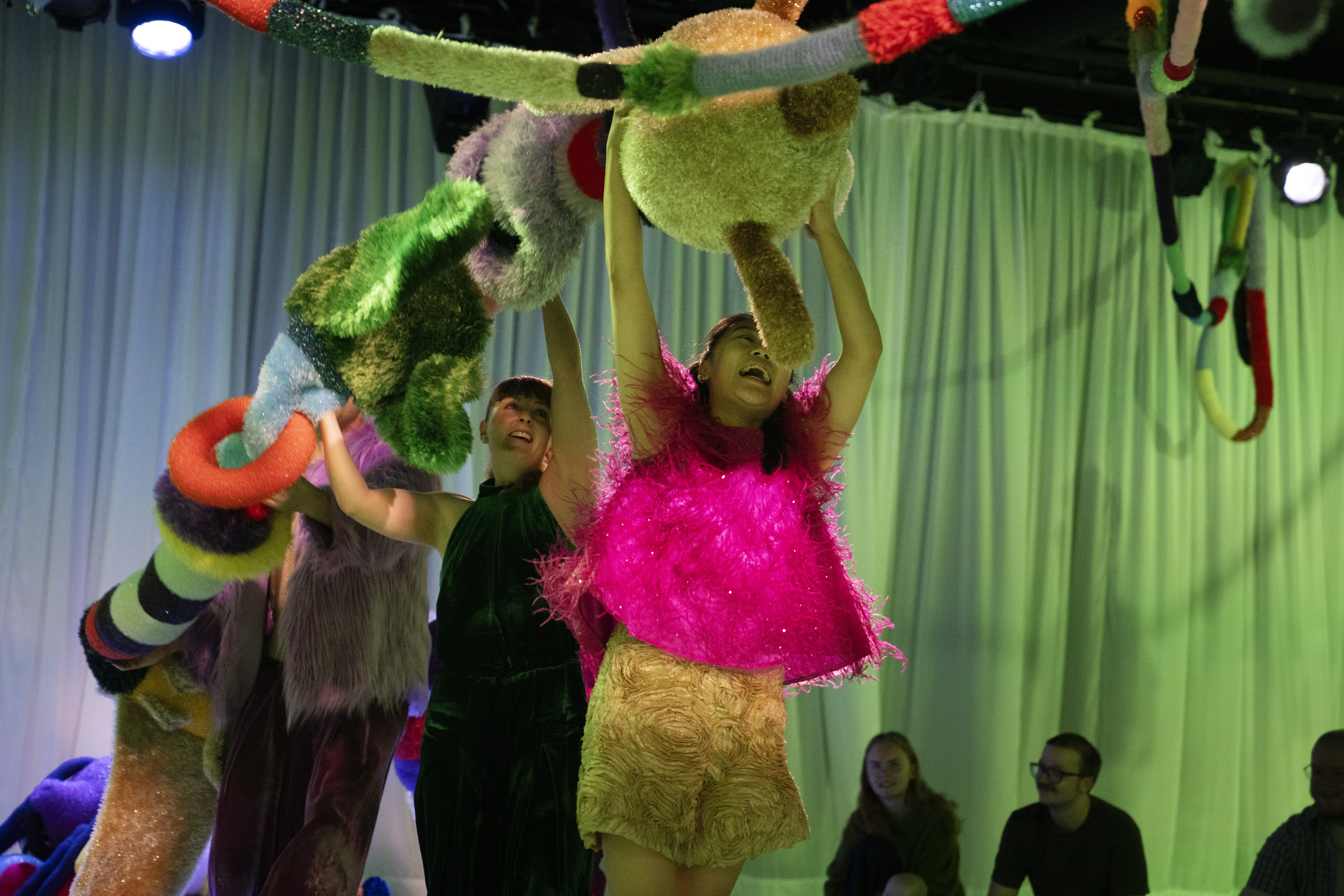Performers holding a big textured shoe over their heads and moving with it