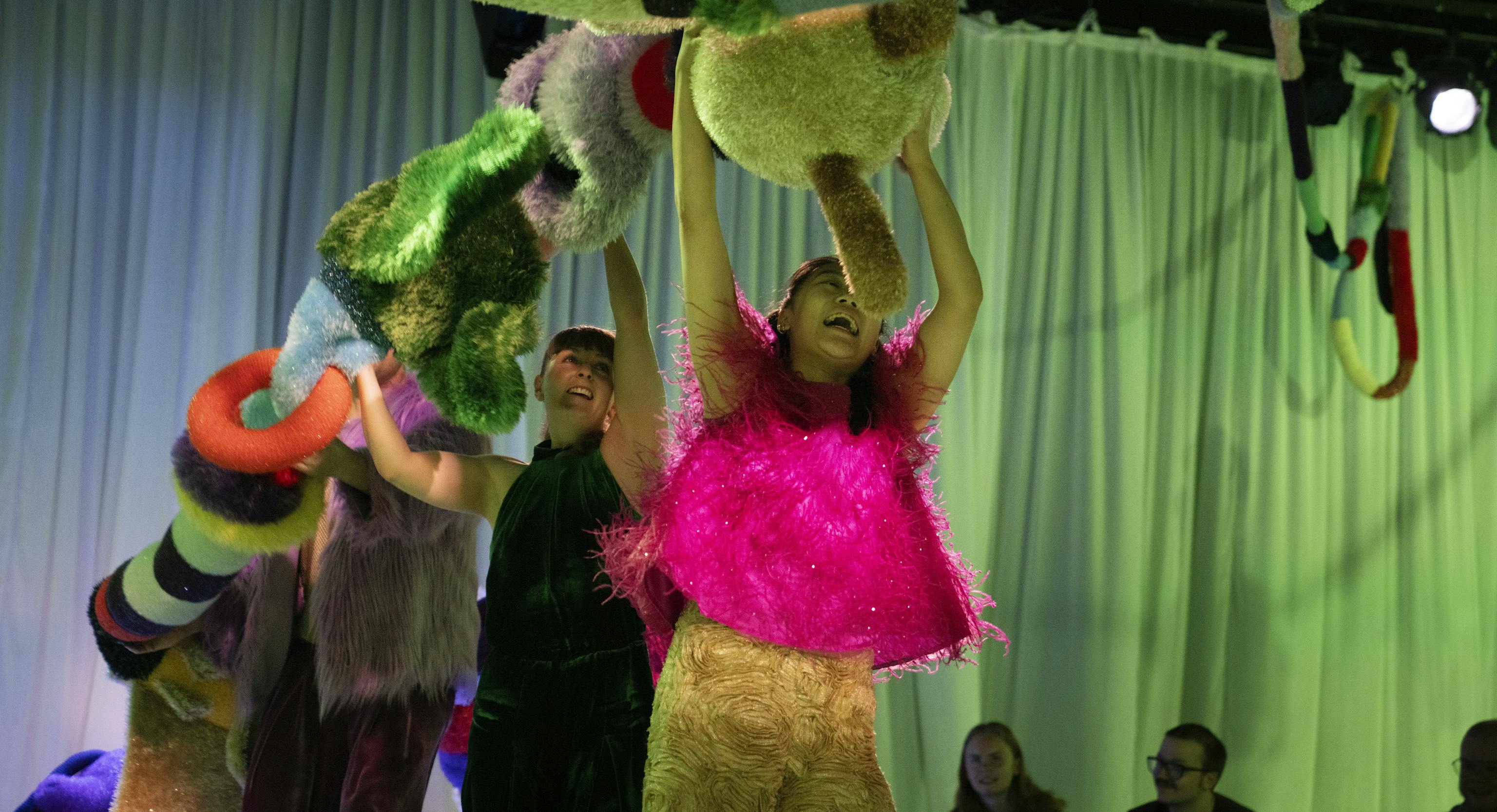 Performers holding a big textured shoe over their heads and moving with it