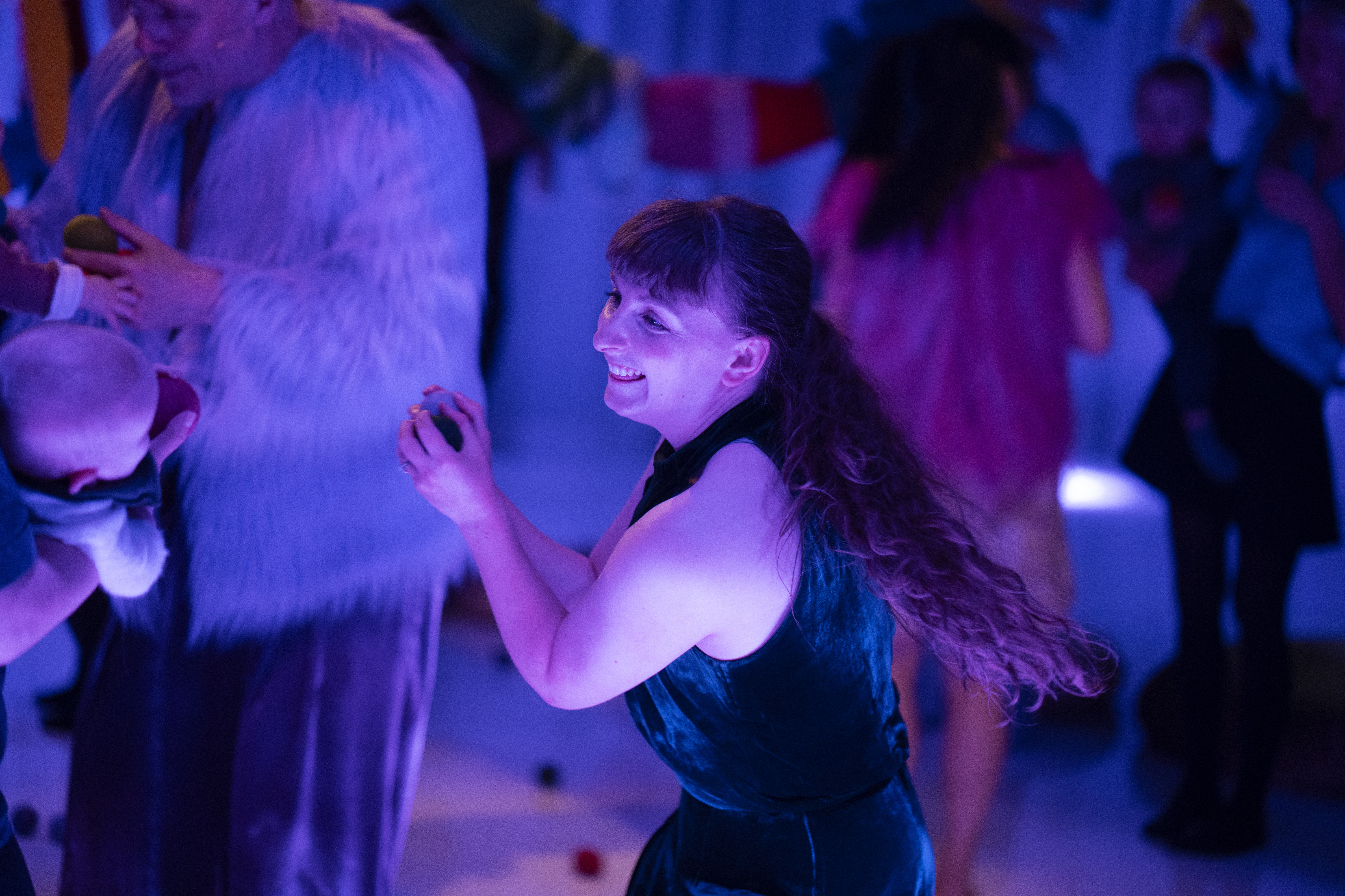 Babies and adults dancing in a dimly lit room