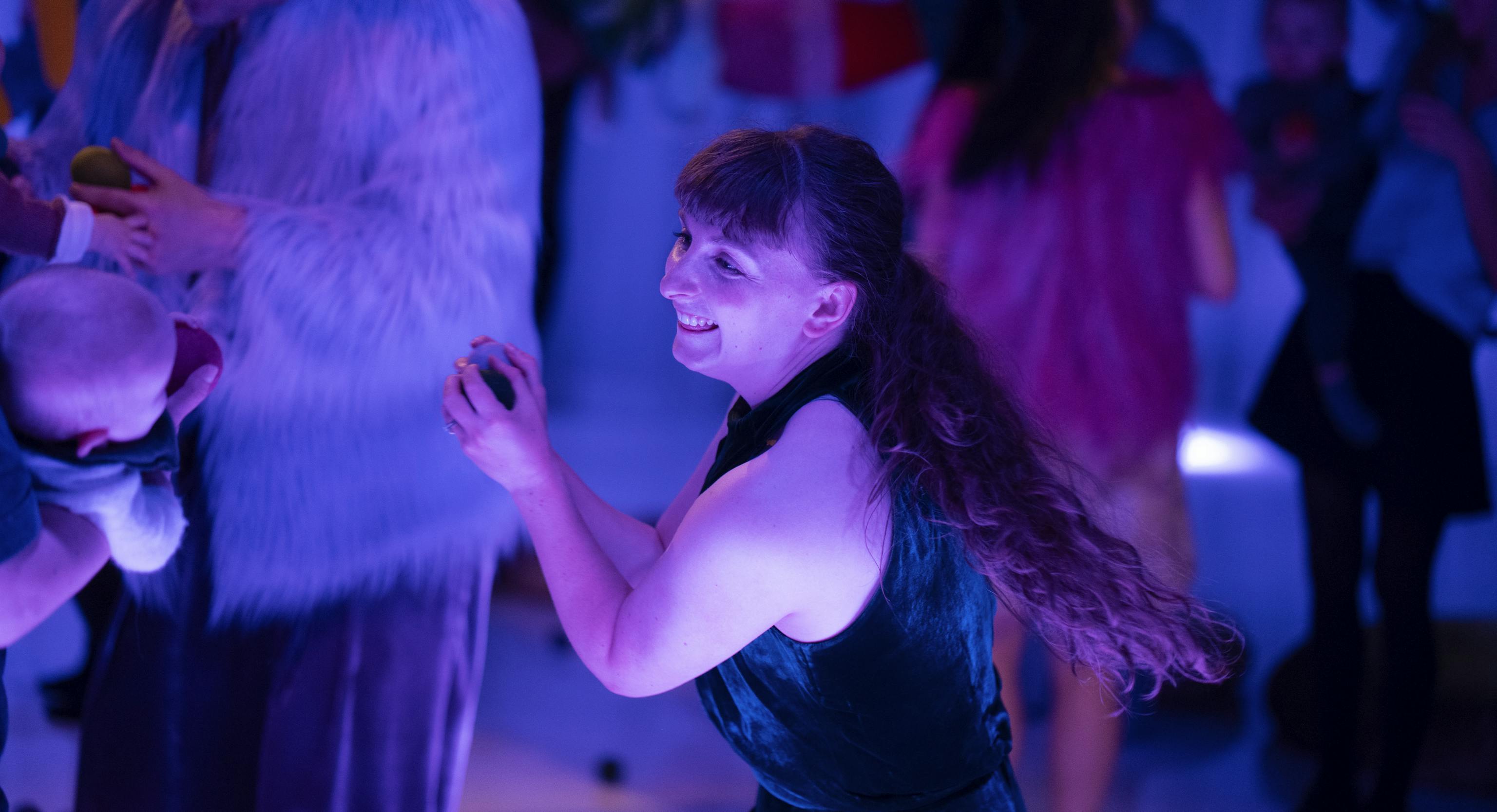 Babies and adults dancing in a dimly lit room