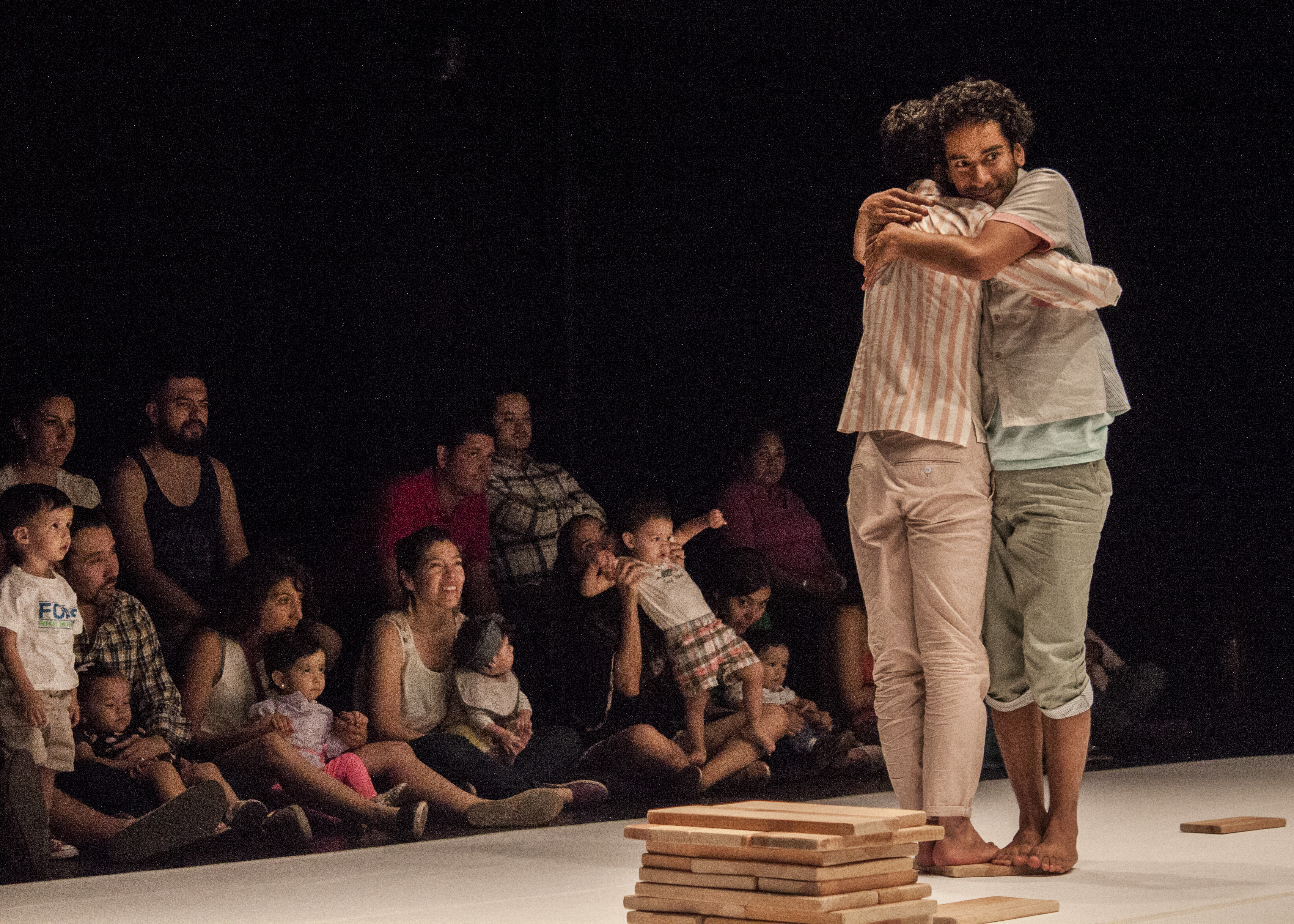 Two performers hugging in front of an audience 