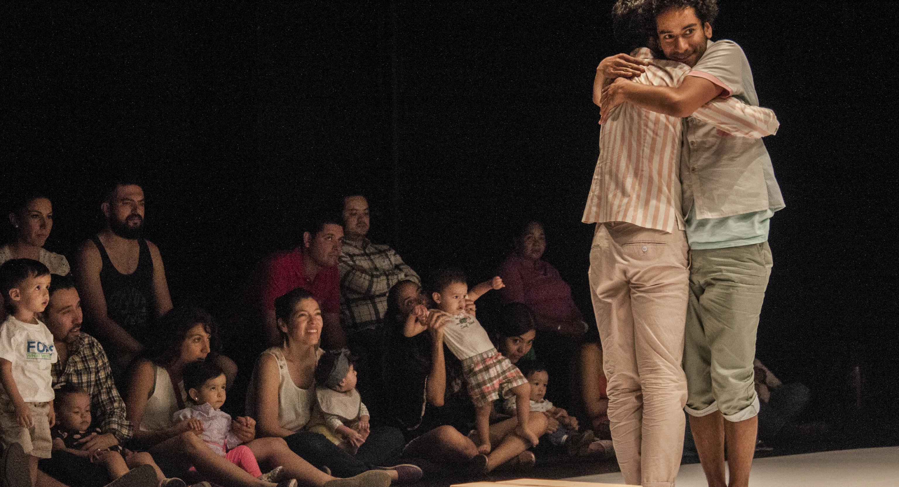 Two performers hugging in front of an audience