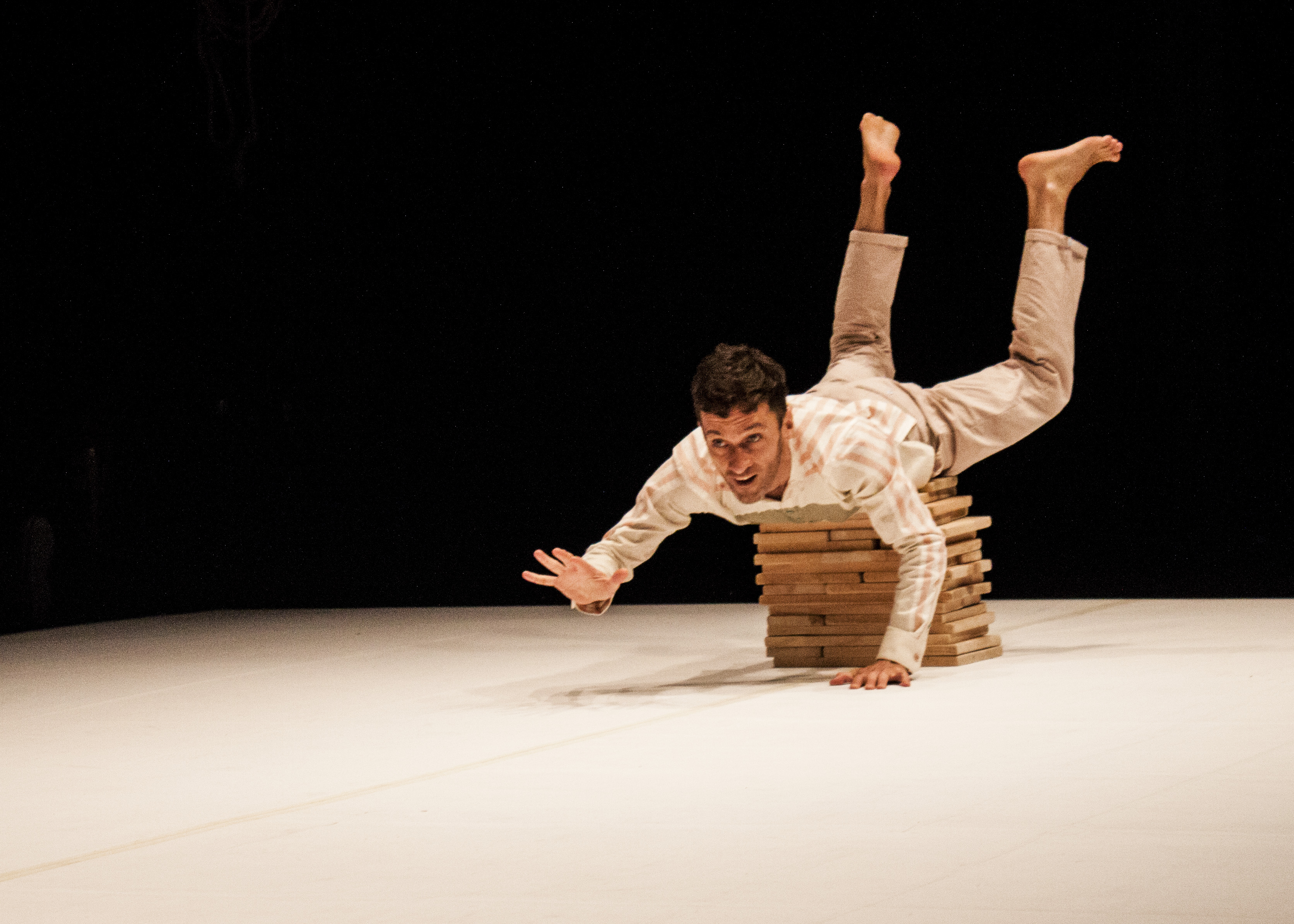 A performer on stage balancing on a pile of blocks