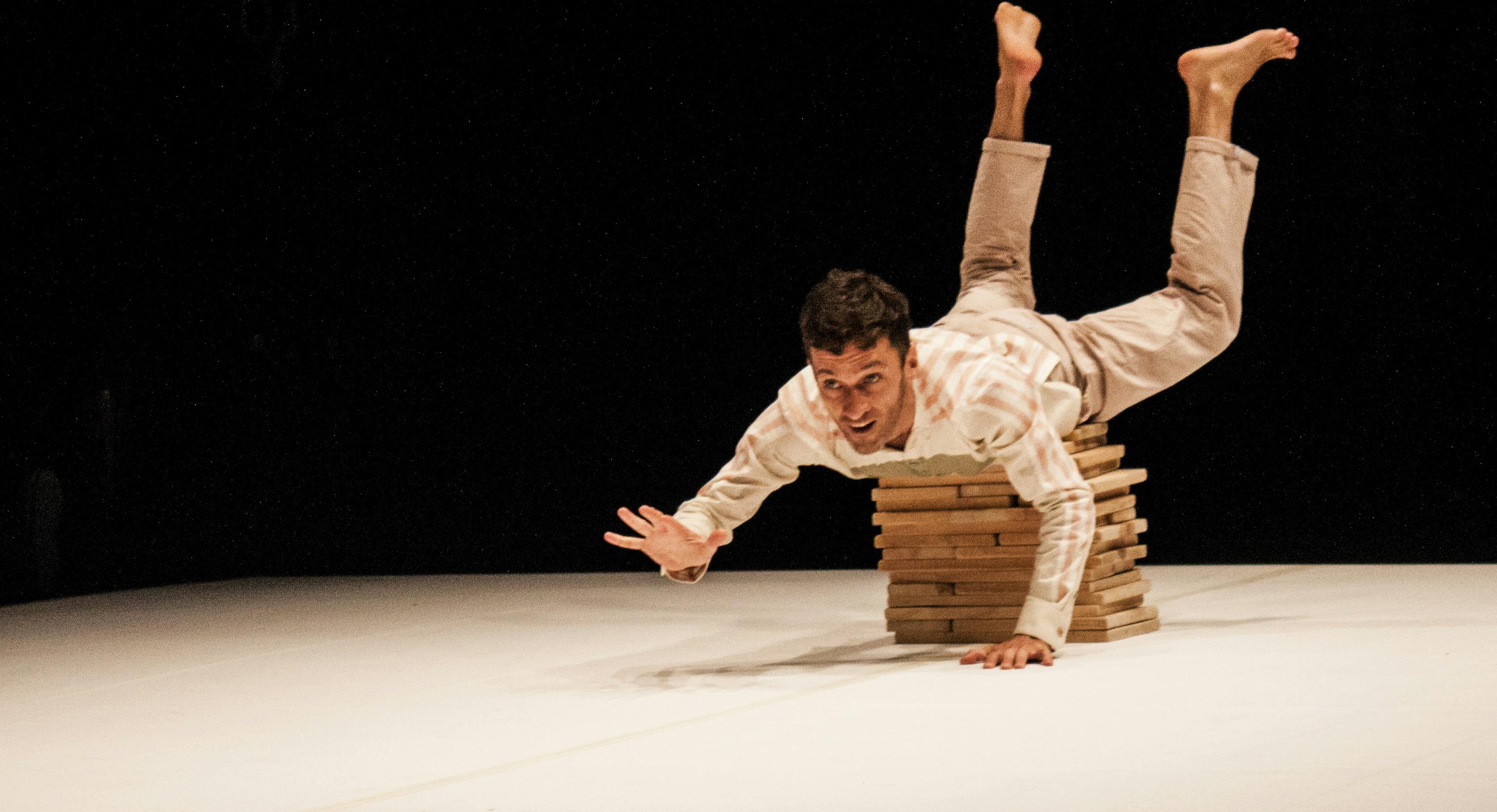 A performer on stage balancing on a pile of blocks