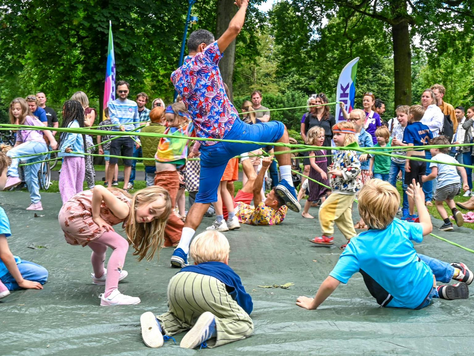A performer and children tangled with a green string in a park