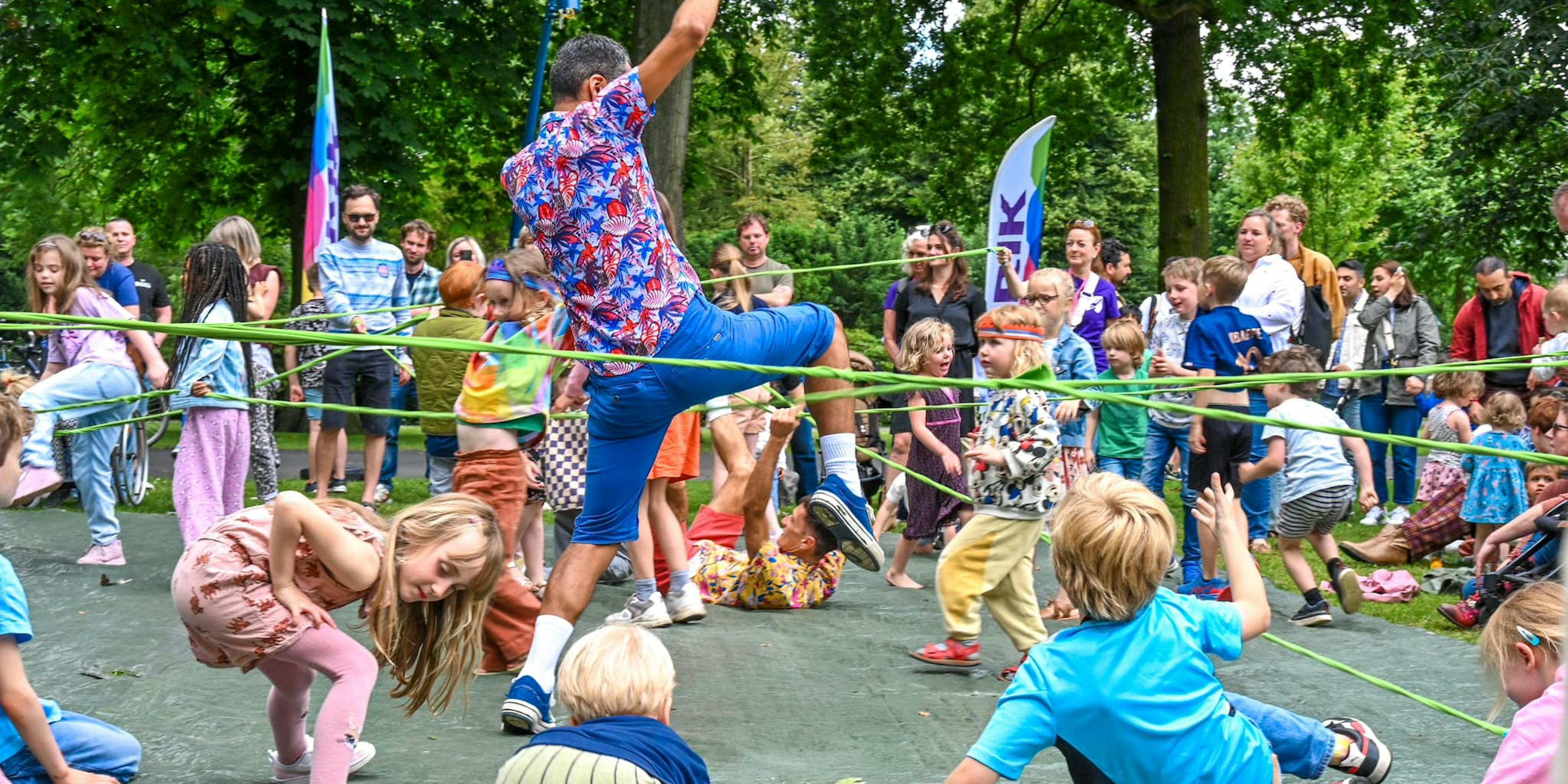 A performer and children tangled with a green string in a park