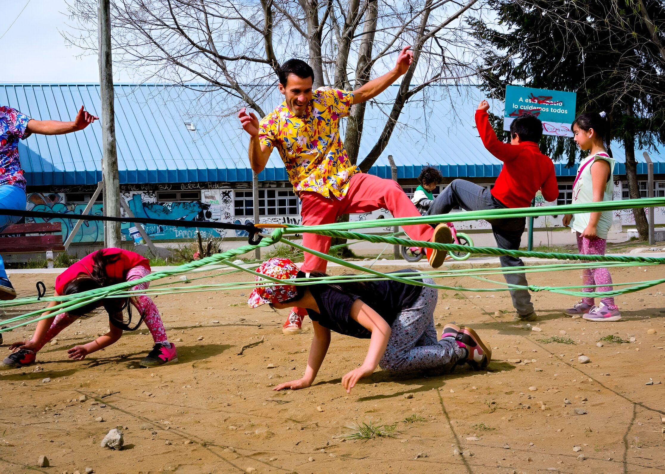 A performer is jumping over rope that is tangled. Around them people are on the floor or standing trying to jump over the rope