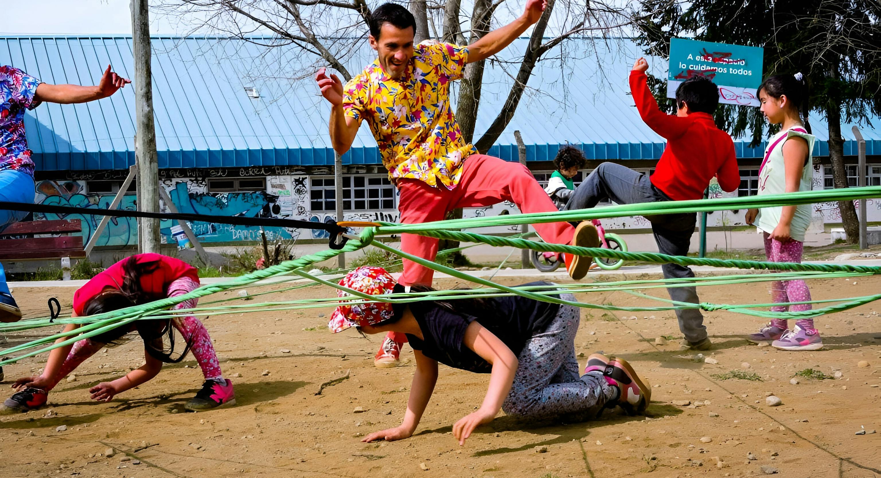 A performer is jumping over rope that is tangled. Around them people are on the floor or standing trying to jump over the rope