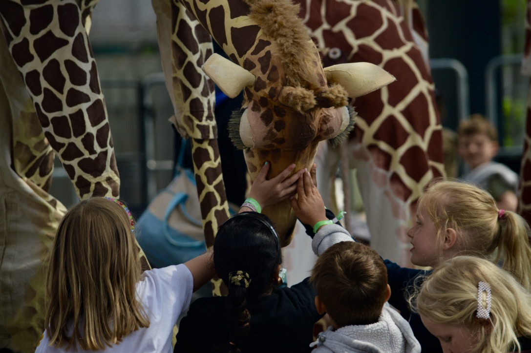 Young children interact with a giraffe, touching it's head