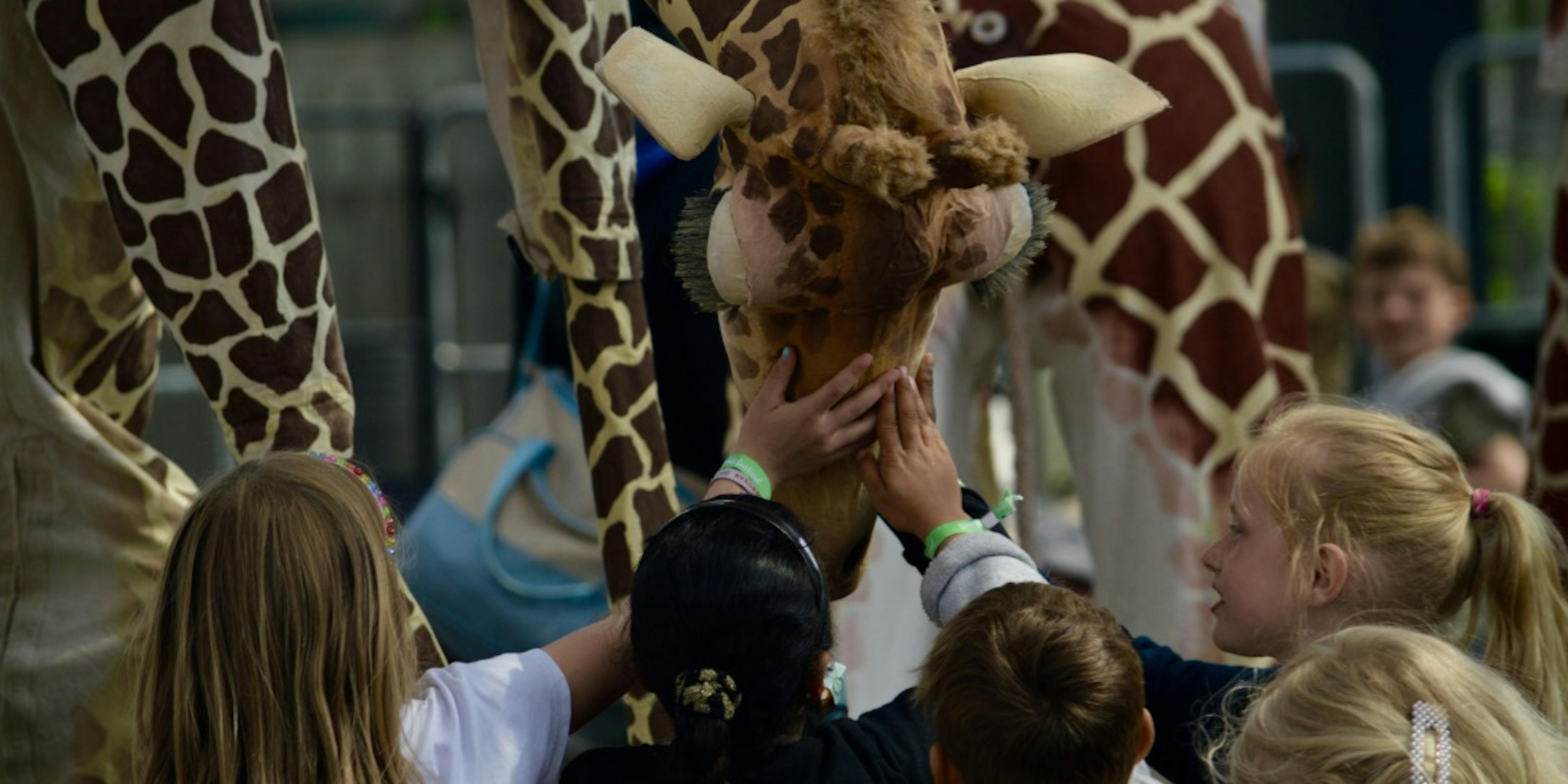Young children interact with a giraffe, touching it's head