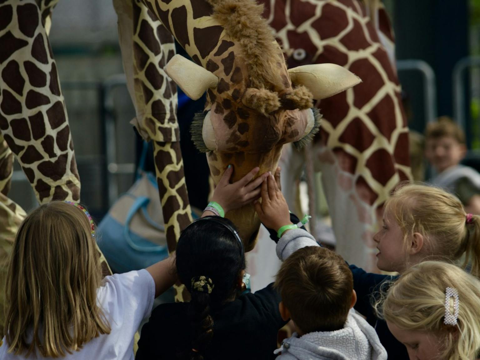Young children interact with a giraffe, touching it's head