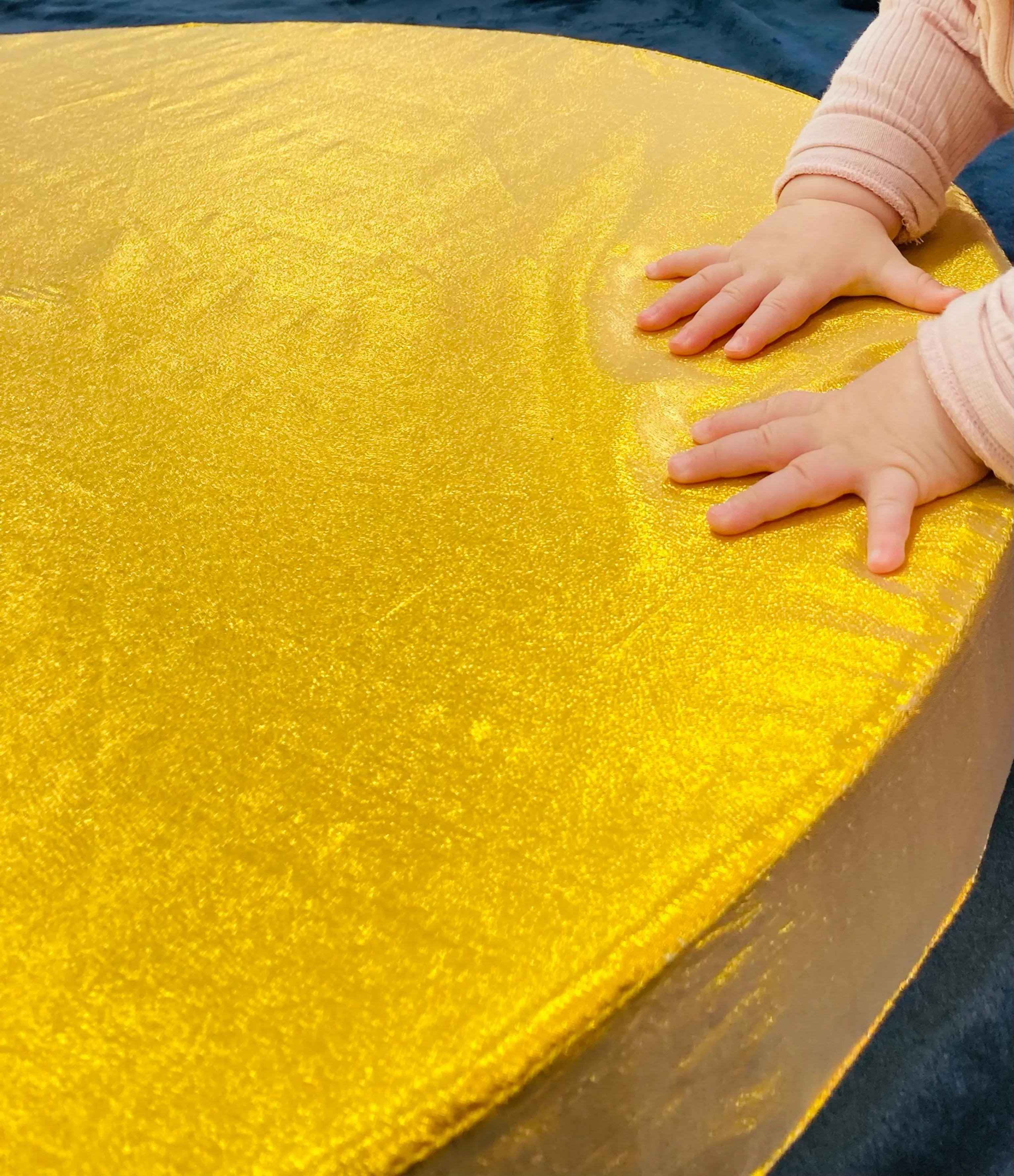 A baby touching a golden piece on material