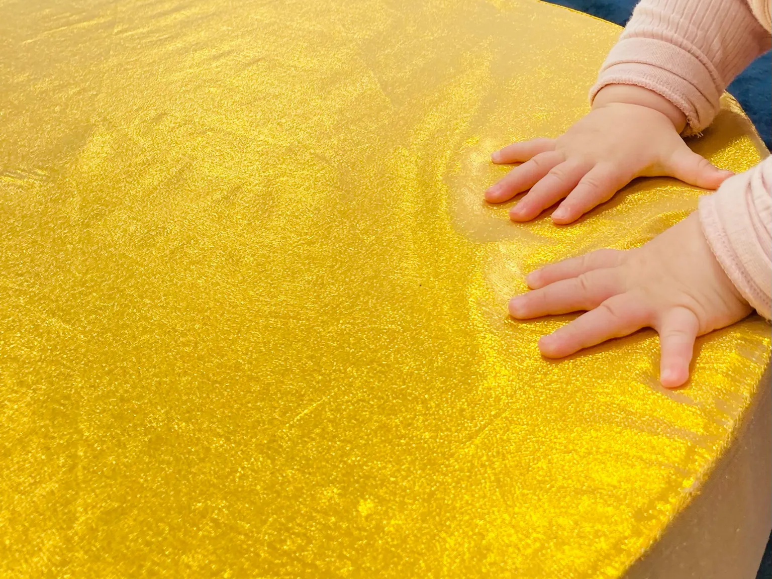 A baby touching a golden piece on material