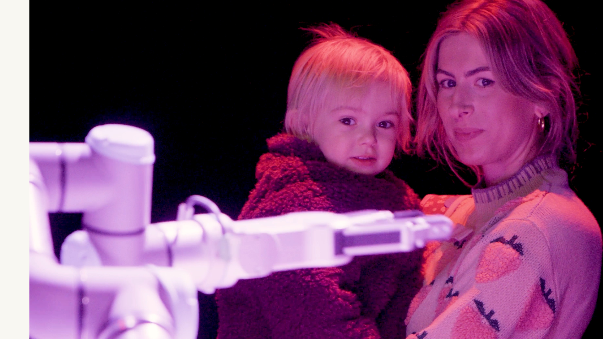 A young child and their parent/carer looking at a robot 
