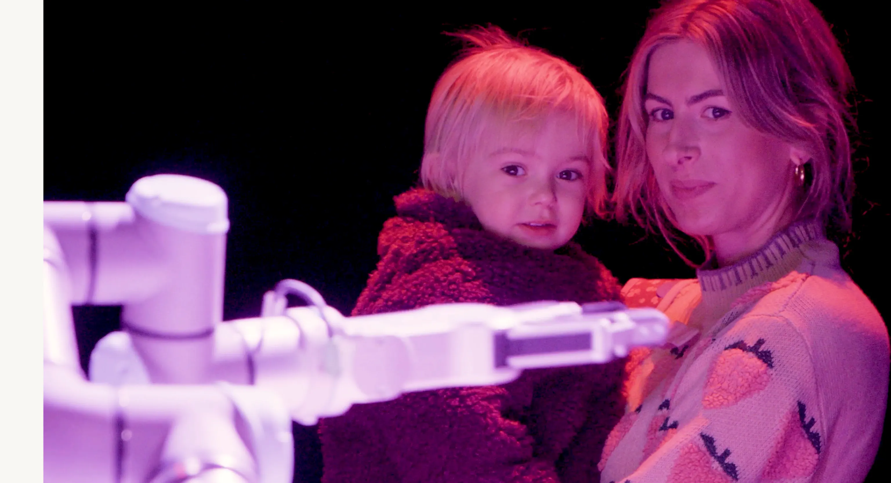 A young child and their parent/carer looking at a robot