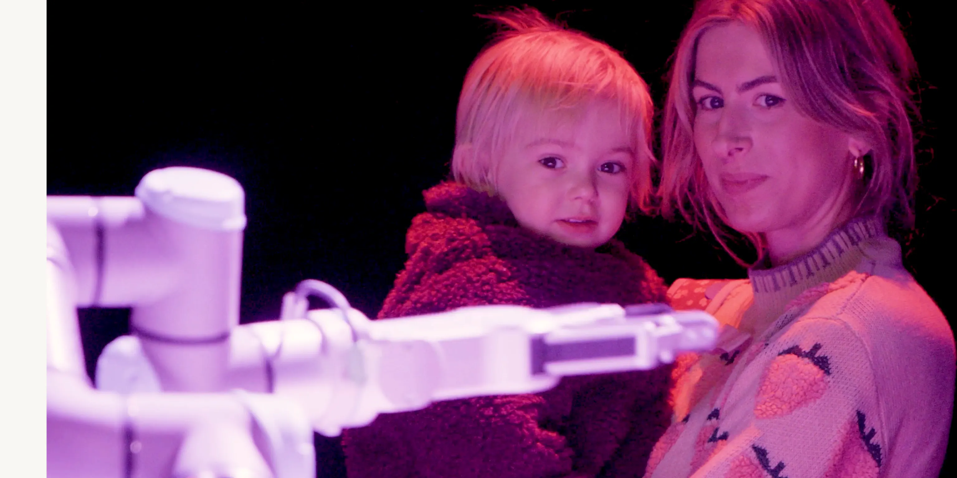 A young child and their parent/carer looking at a robot