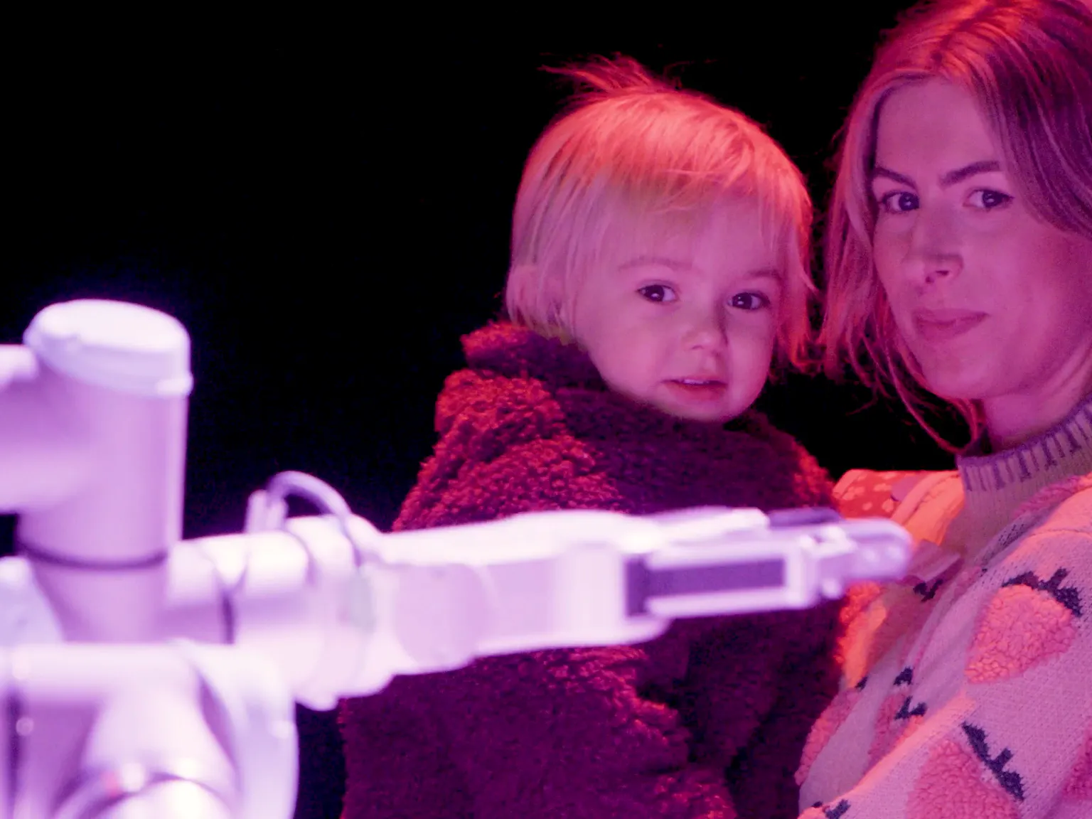 A young child and their parent/carer looking at a robot