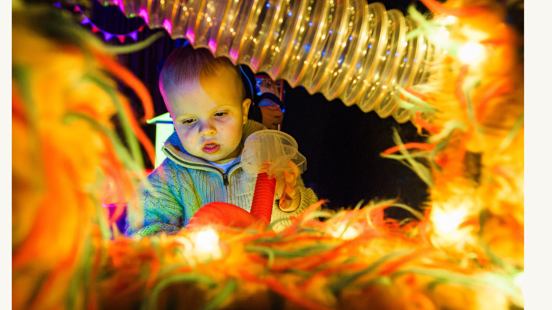 A young child interacting with lights and textured materials 