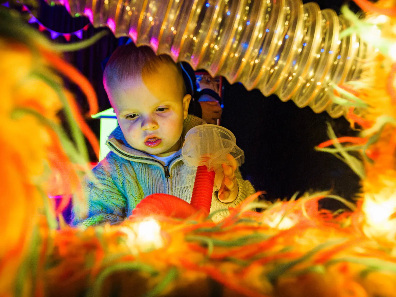 A young child interacting with lights and textured materials