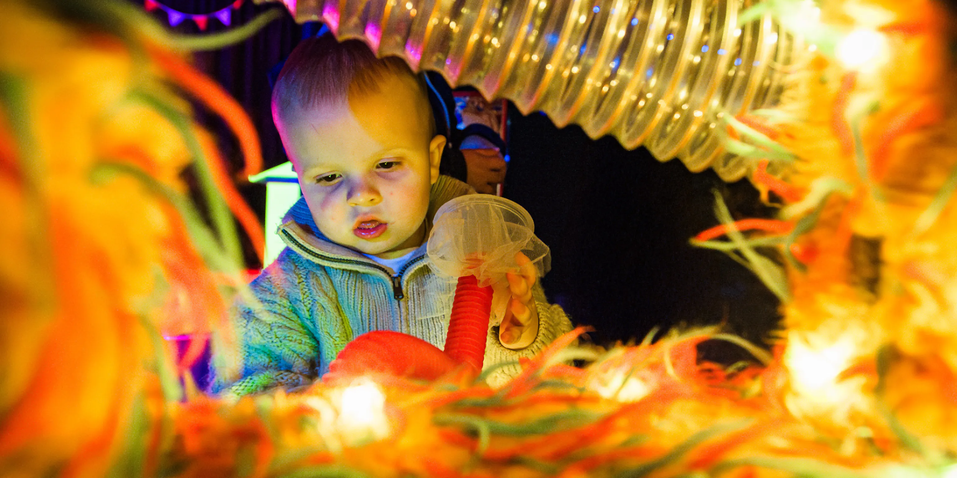 A young child interacting with lights and textured materials