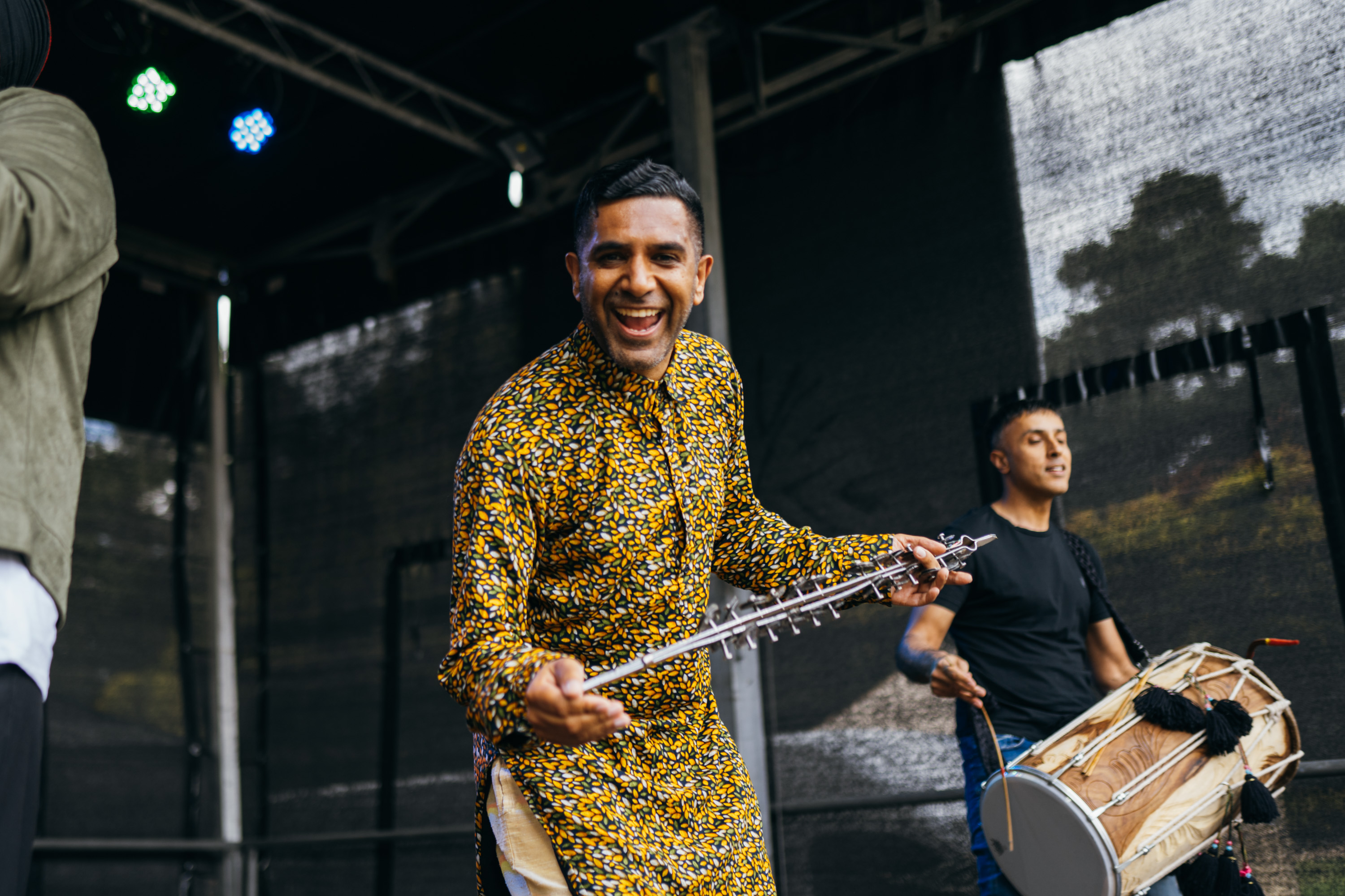 An artist smiling at the camera whilst holding an instrument