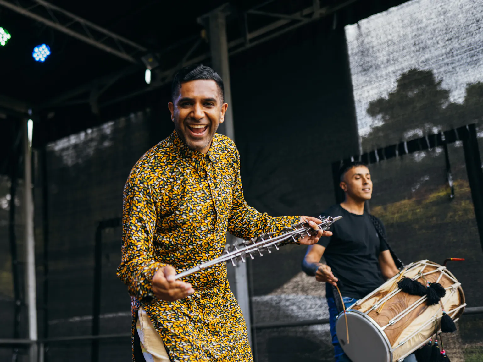 An artist smiling at the camera whilst holding an instrument