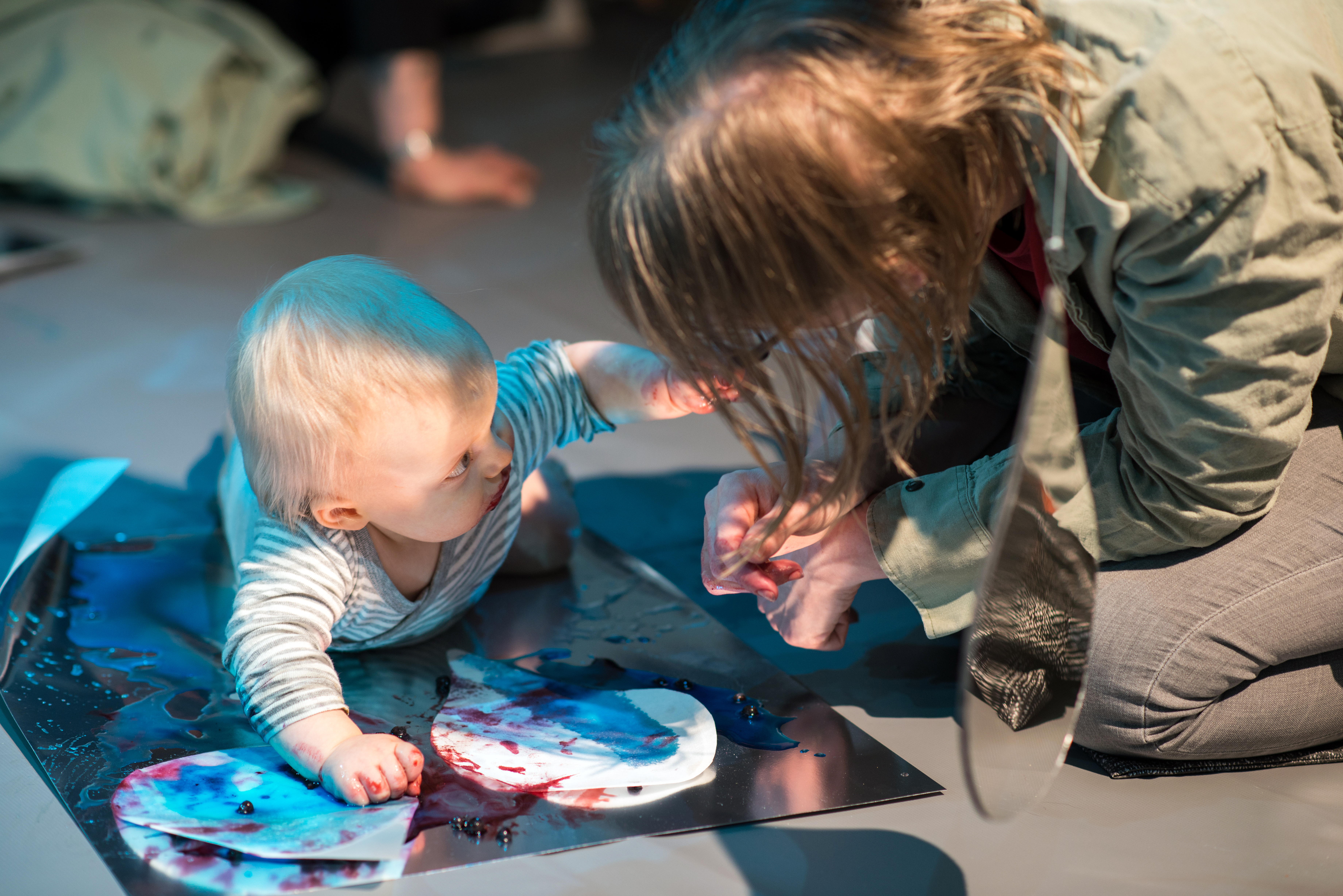 Colour Workshops: a baby lying on their front and engaging with an adult 
