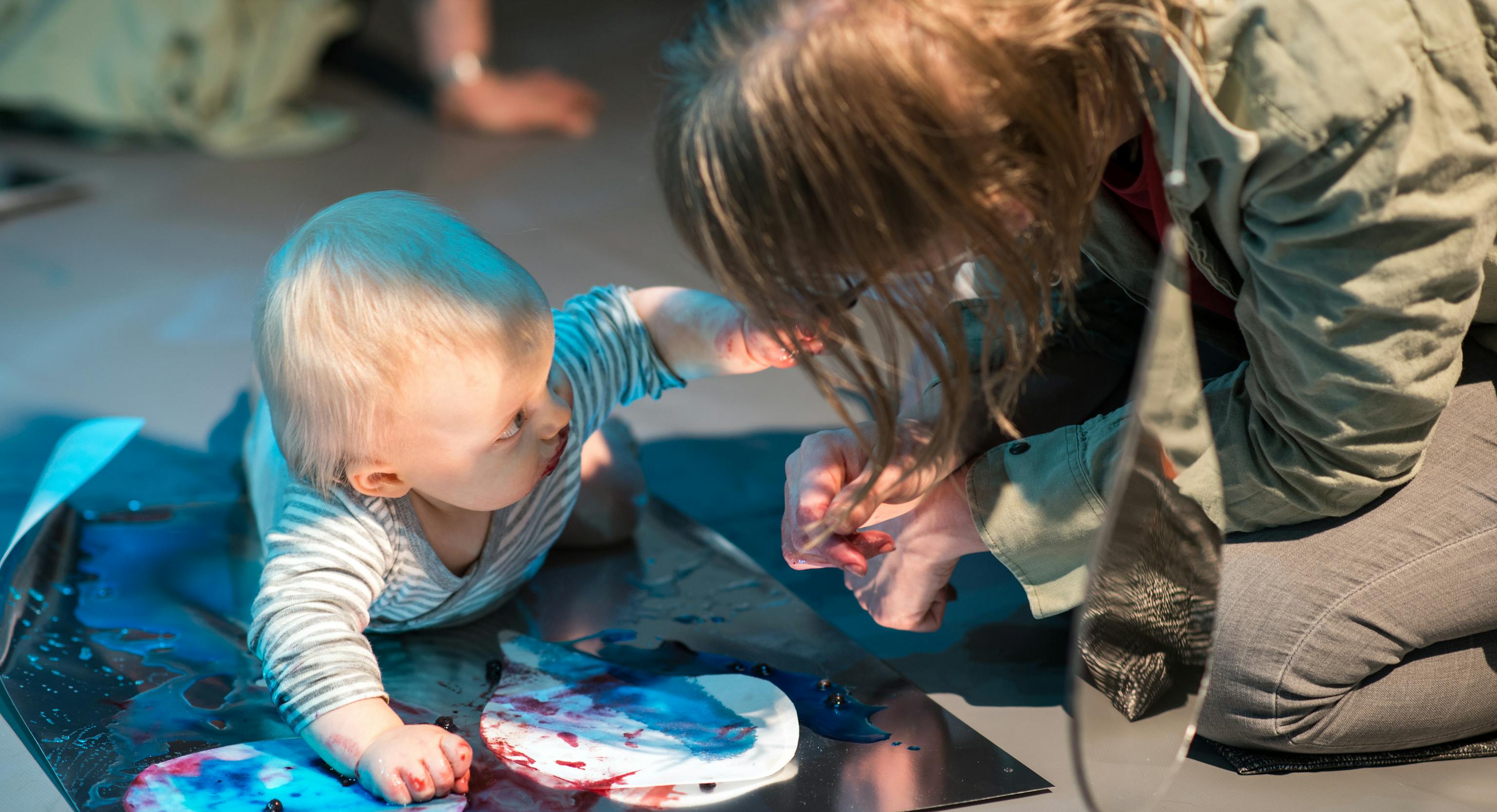Colour Workshops: a baby lying on their front and engaging with an adult