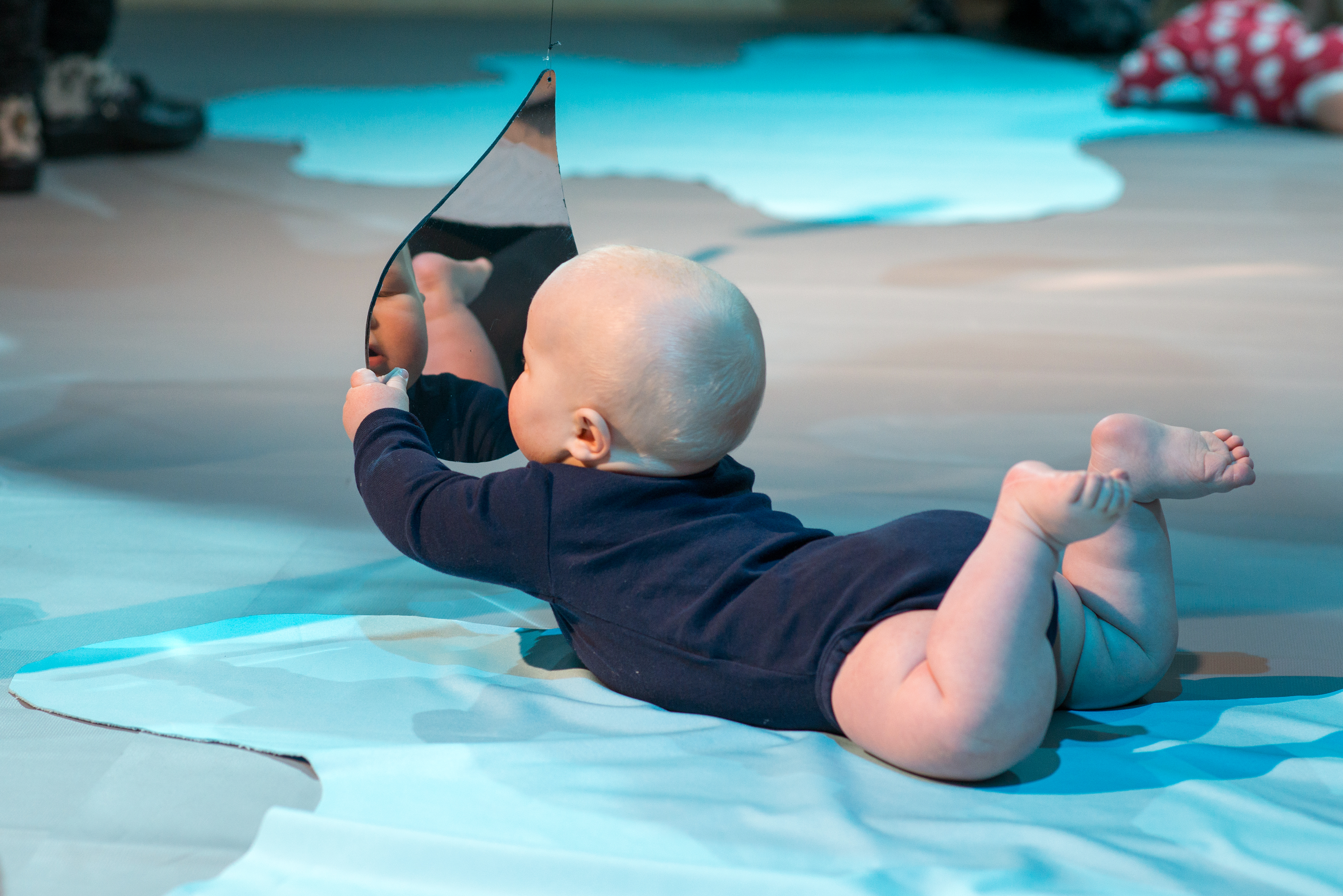 Colour Workshops: a baby lying on their front and holding up a mirror