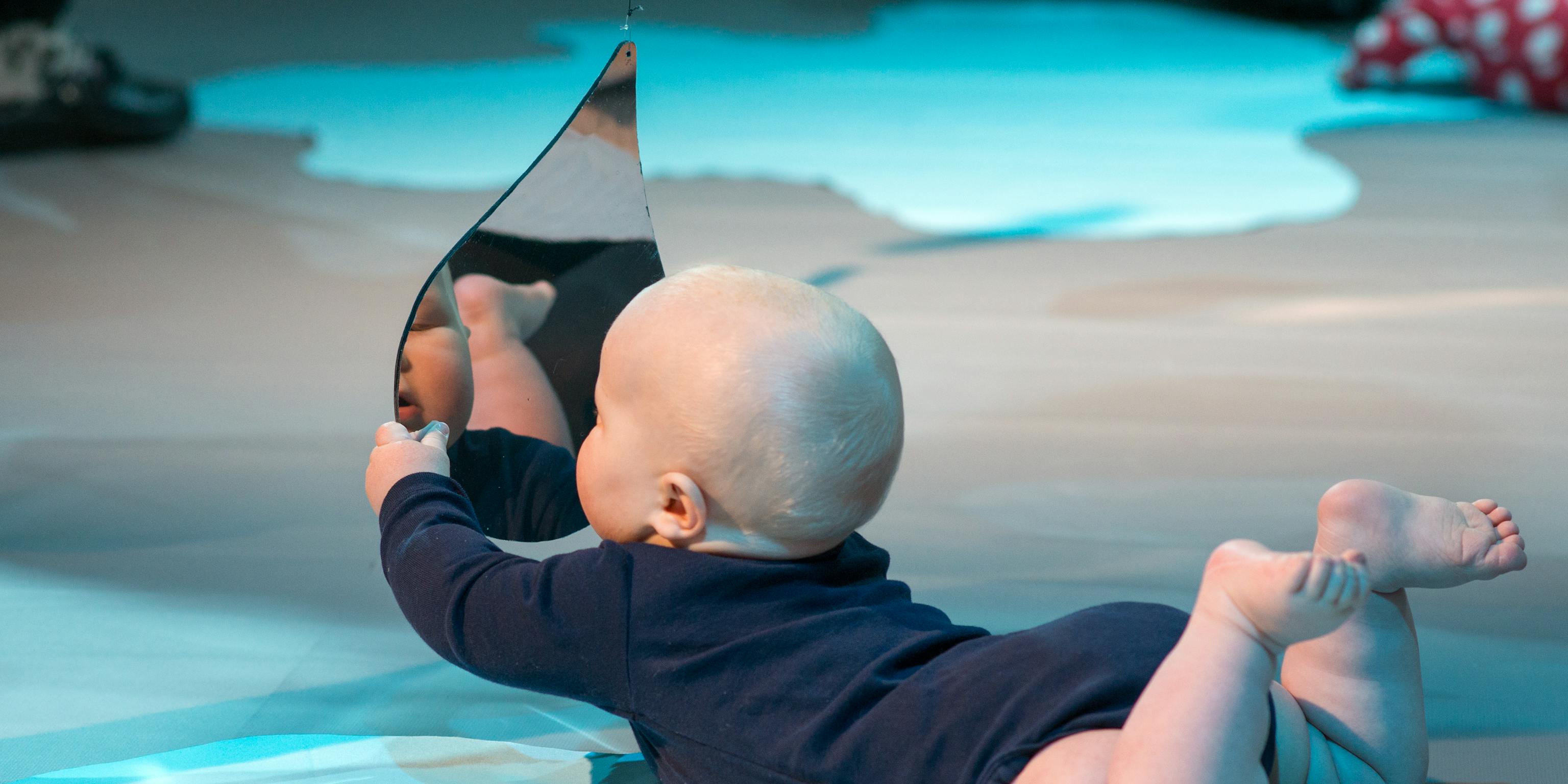 Colour Workshops: a baby lying on their front and holding up a mirror