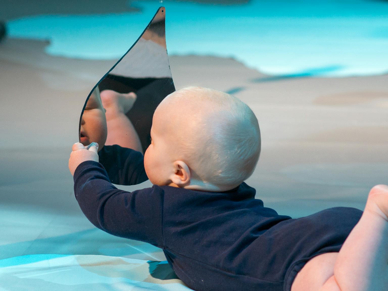 Colour Workshops: a baby lying on their front and holding up a mirror