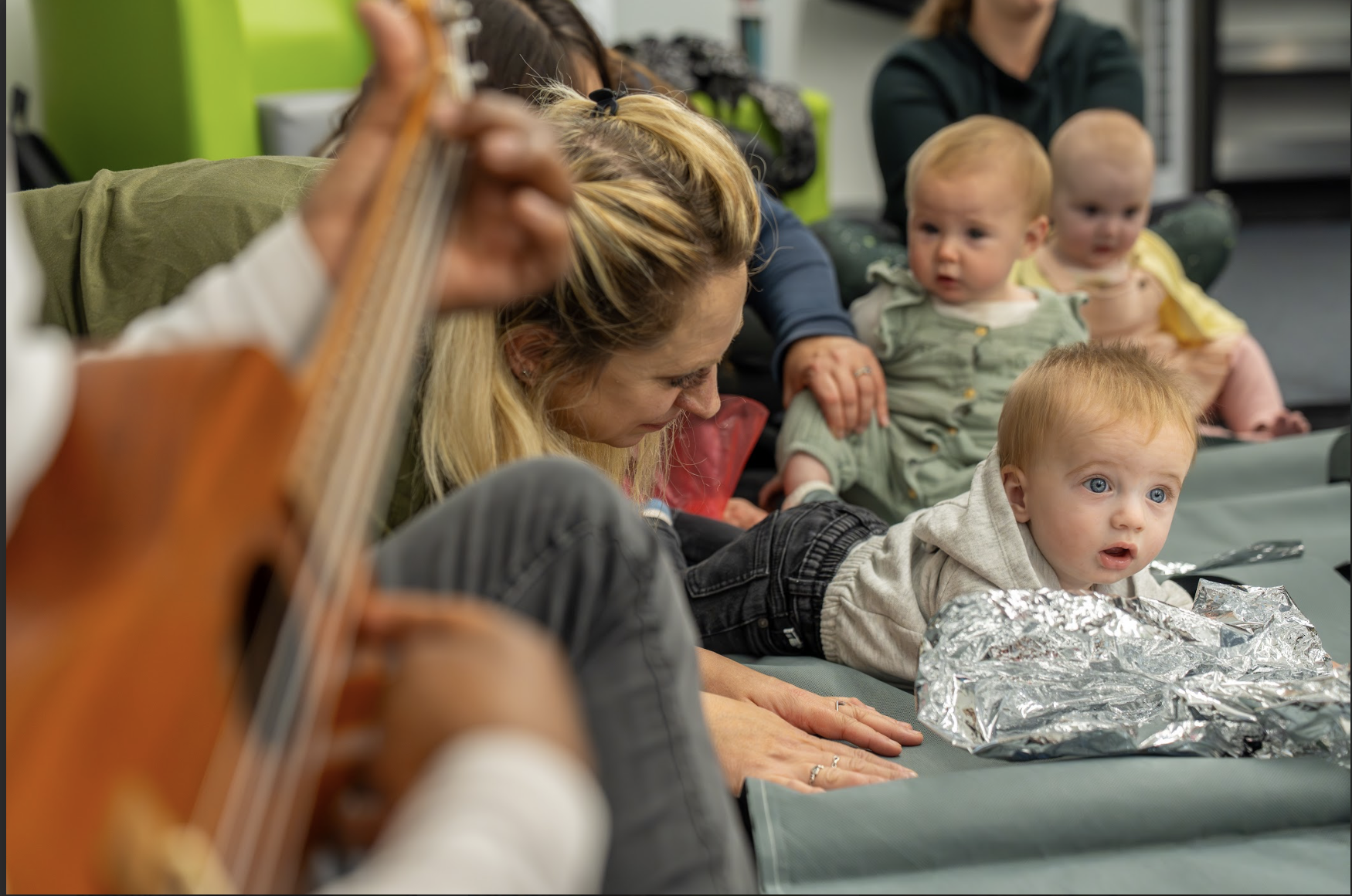 A group of children and parents/carers in a Playground session interacting with each other and the artists 